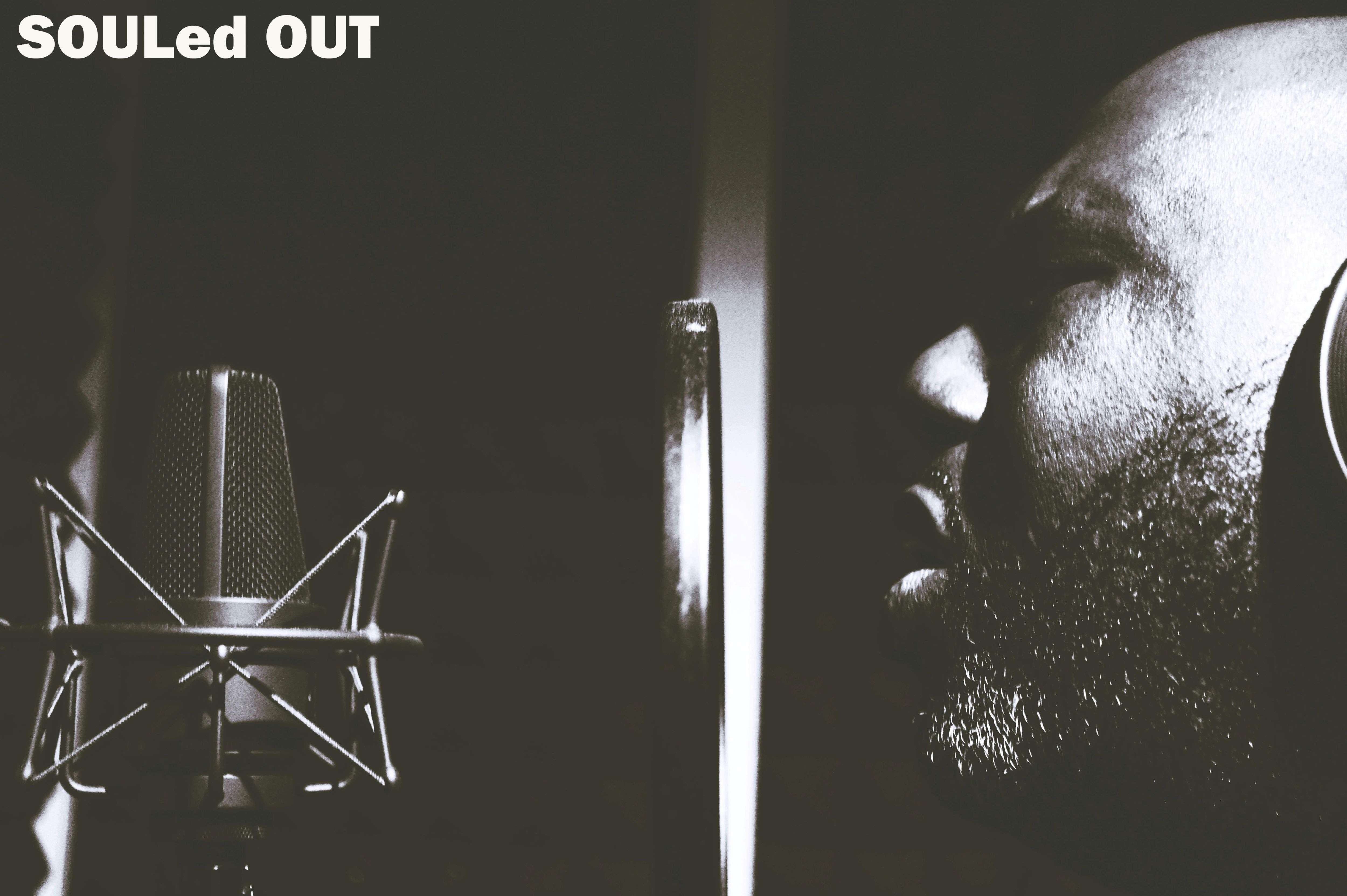 a man is singing into a microphone with the words souled out