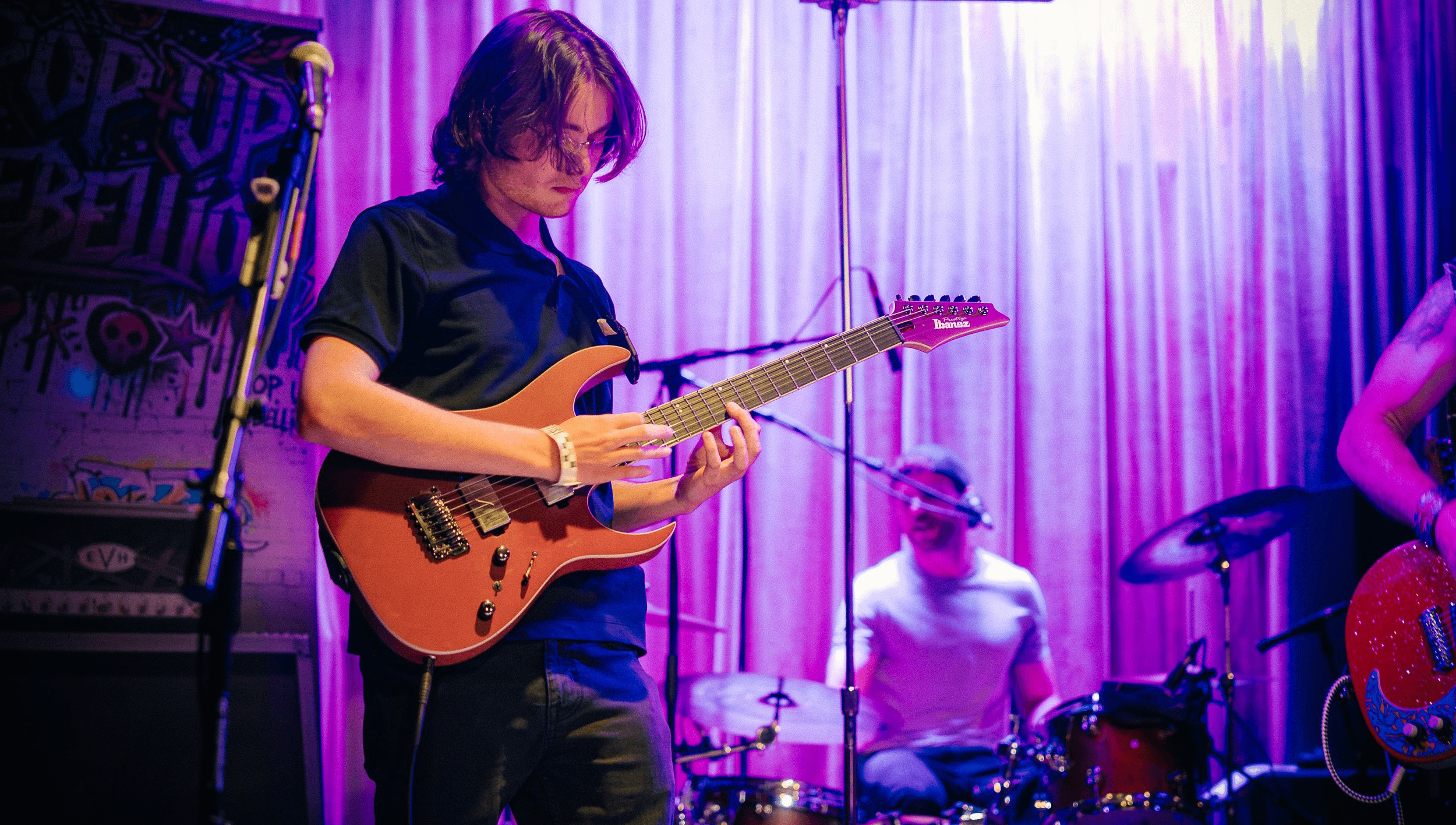 a young man playing an electric guitar in a band