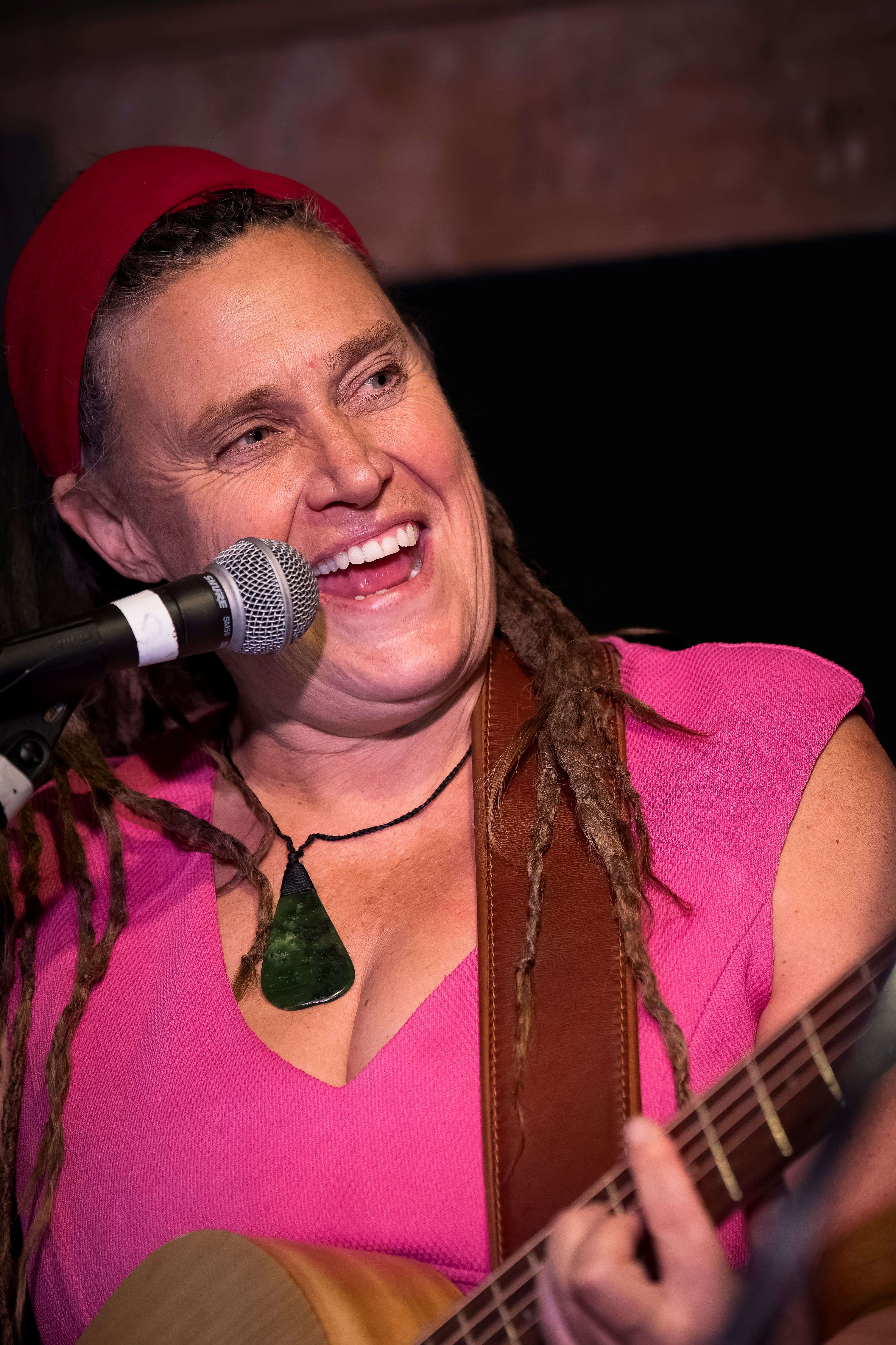 a woman with dreadlocks playing an acoustic guitar