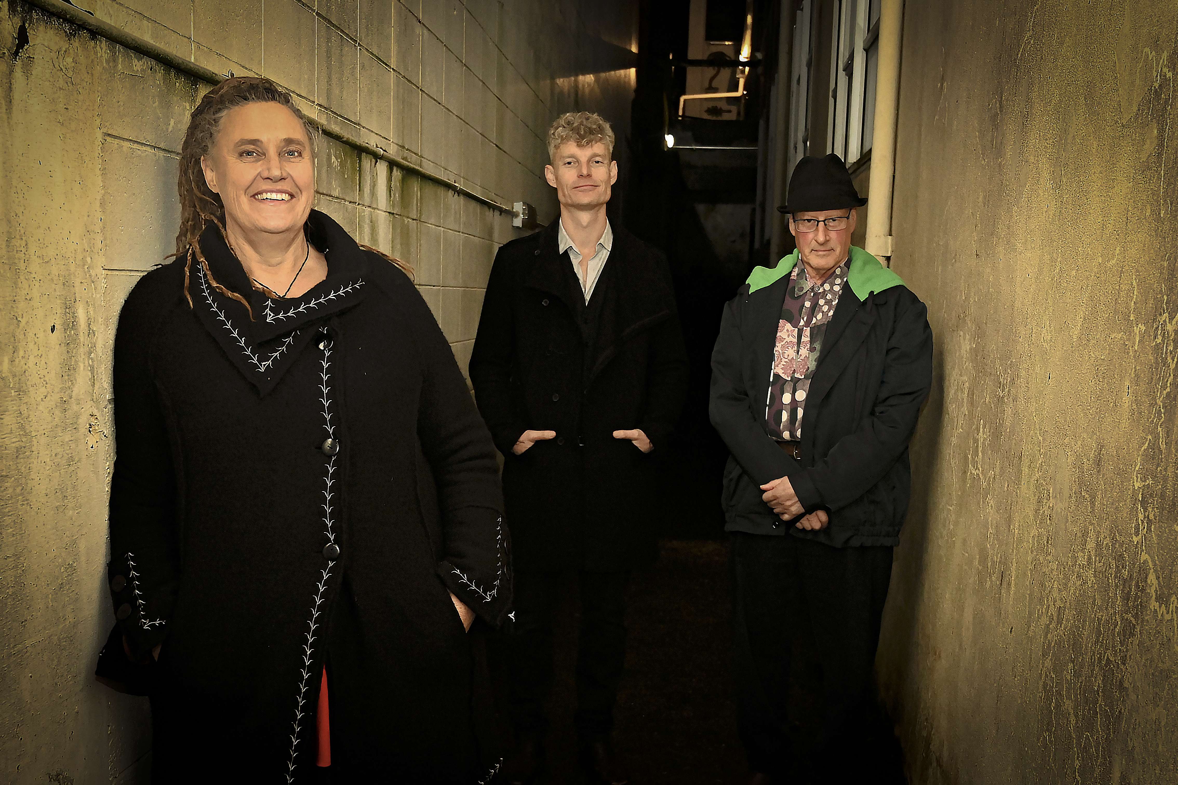three people standing next to each other in an alleyway