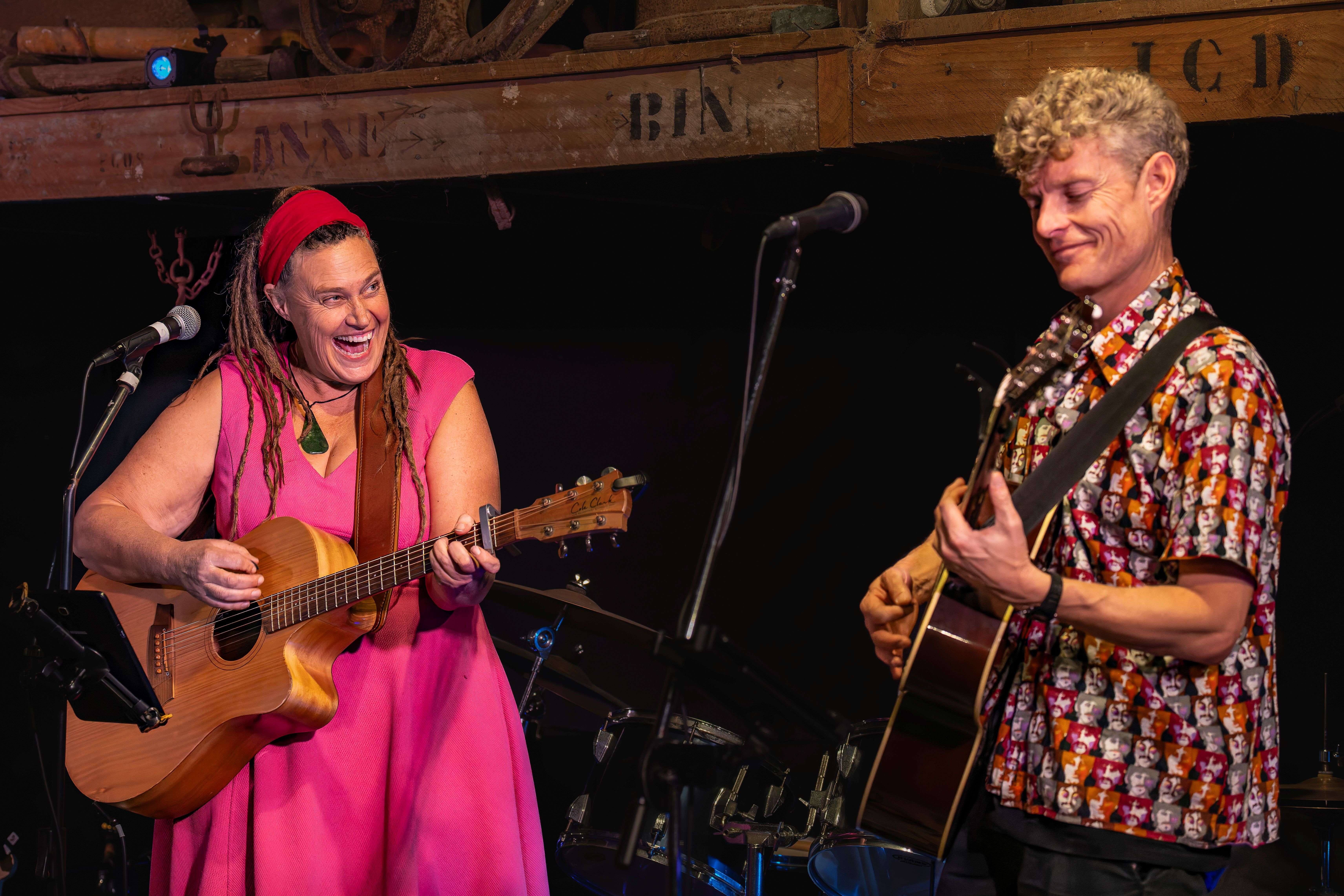 two people singing and playing acoustic guitars