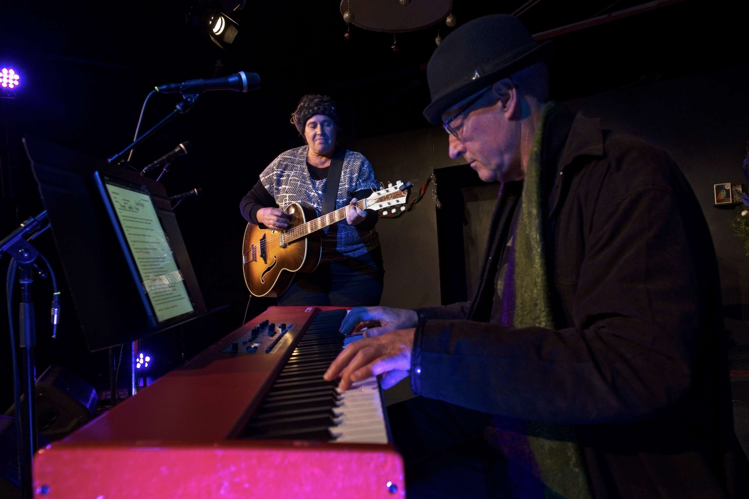 two people playing a keyboard in front of a microphone