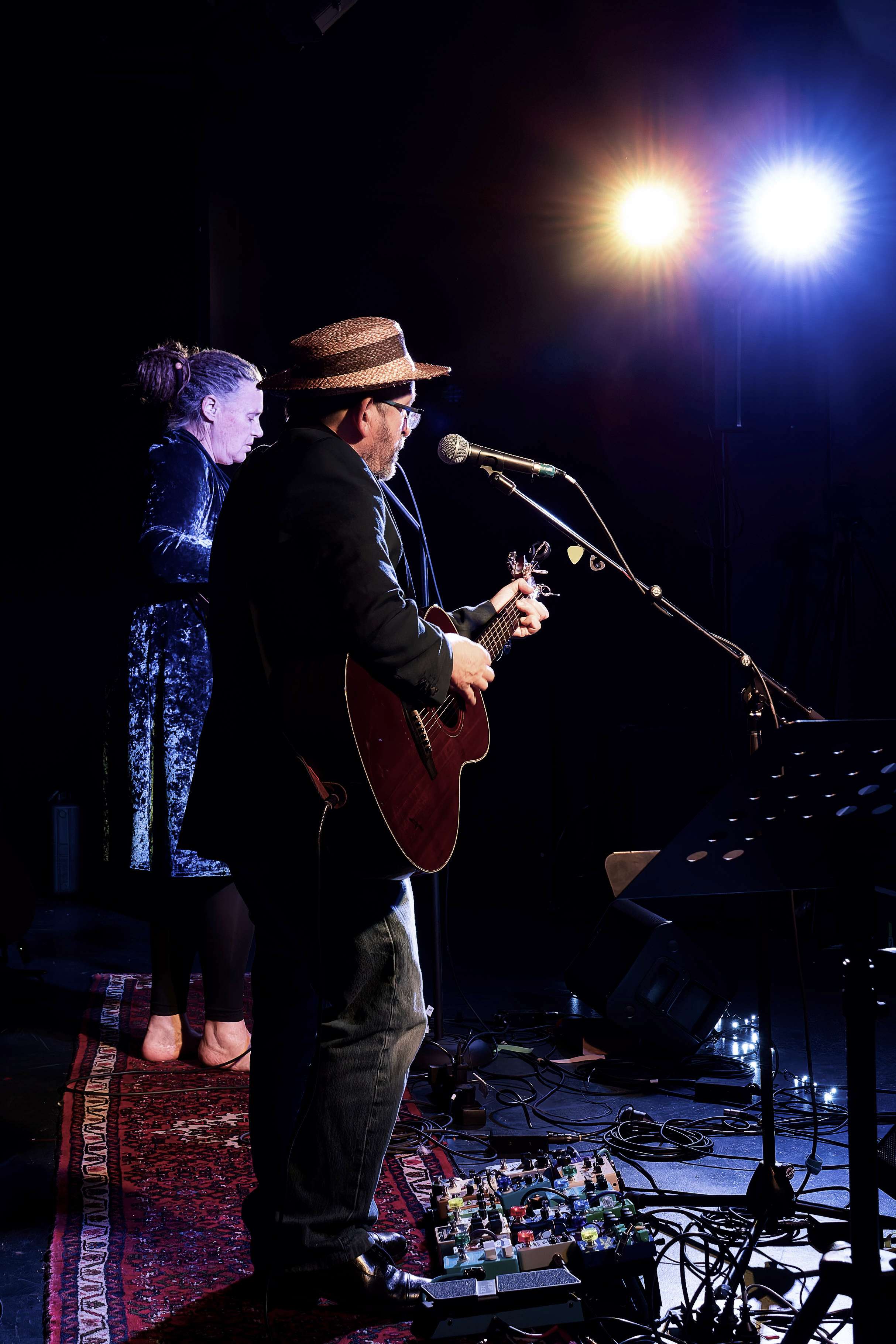 a man in a hat is playing an acoustic guitar