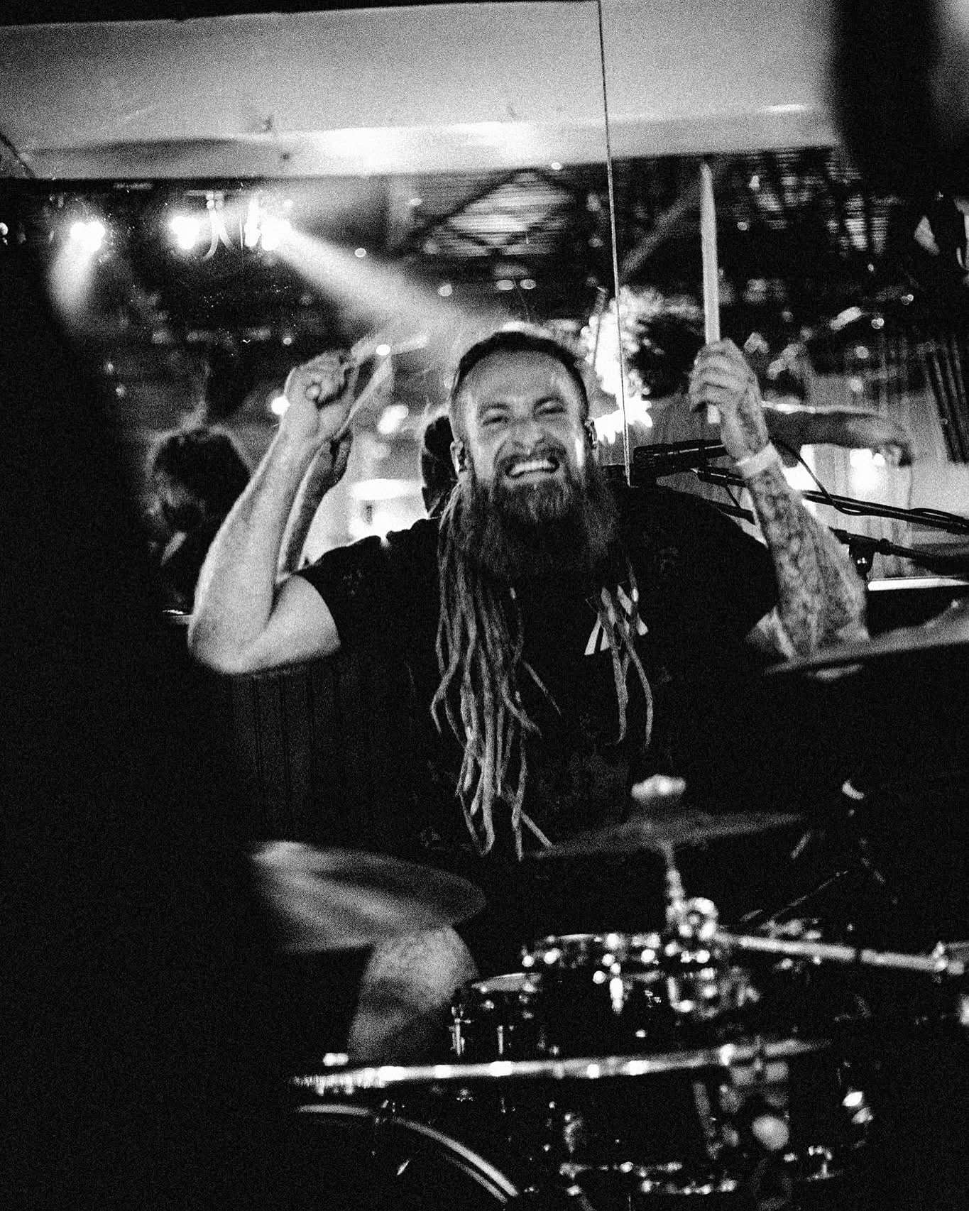 a man with dreadlocks playing drums in a bar