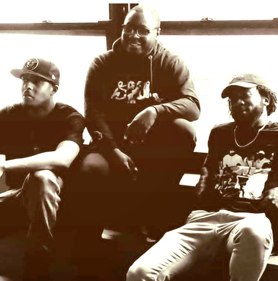 four men sitting on a bench in front of a window