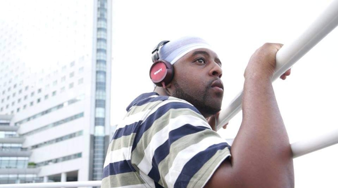 a man with headphones leaning against a railing