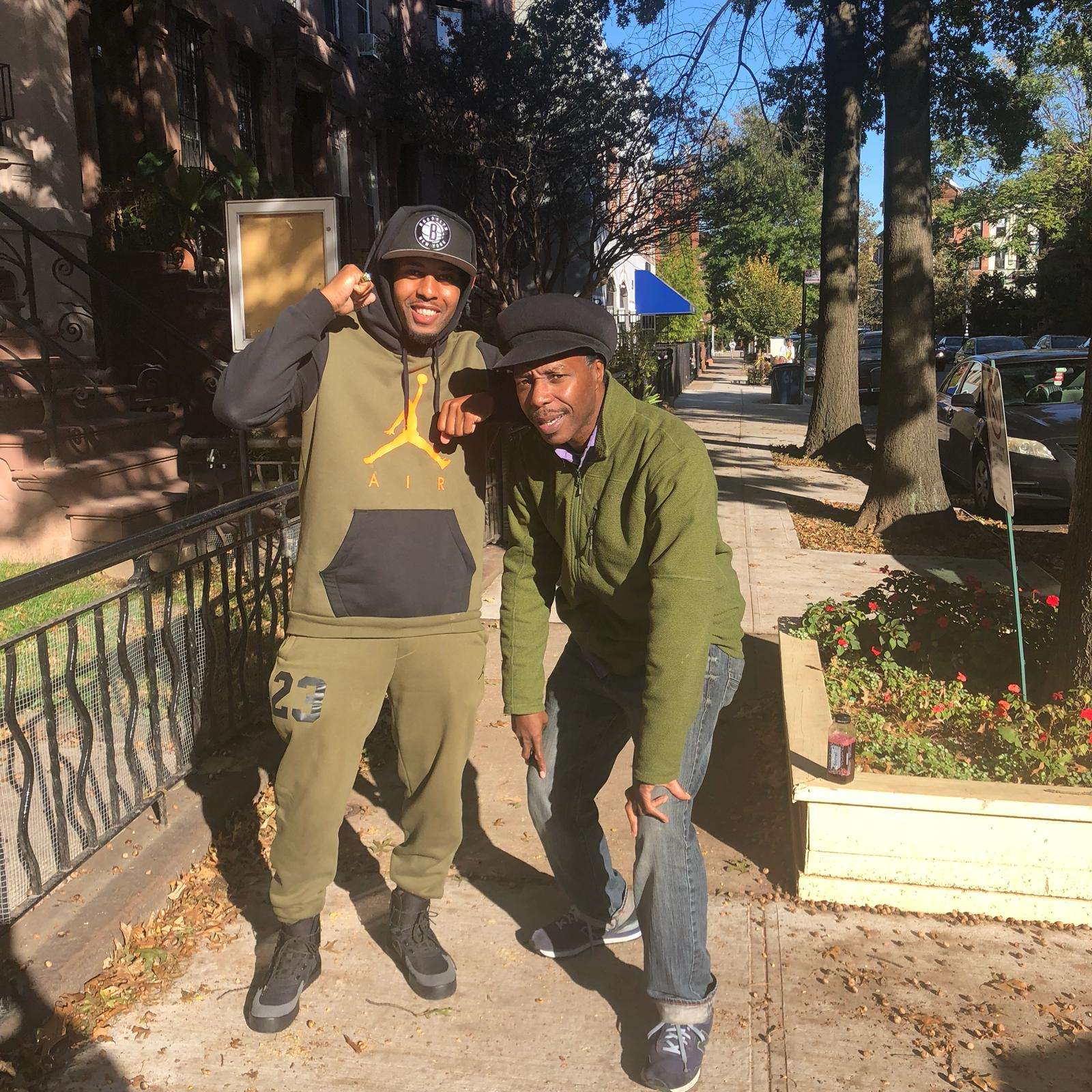 two men standing next to each other on a sidewalk