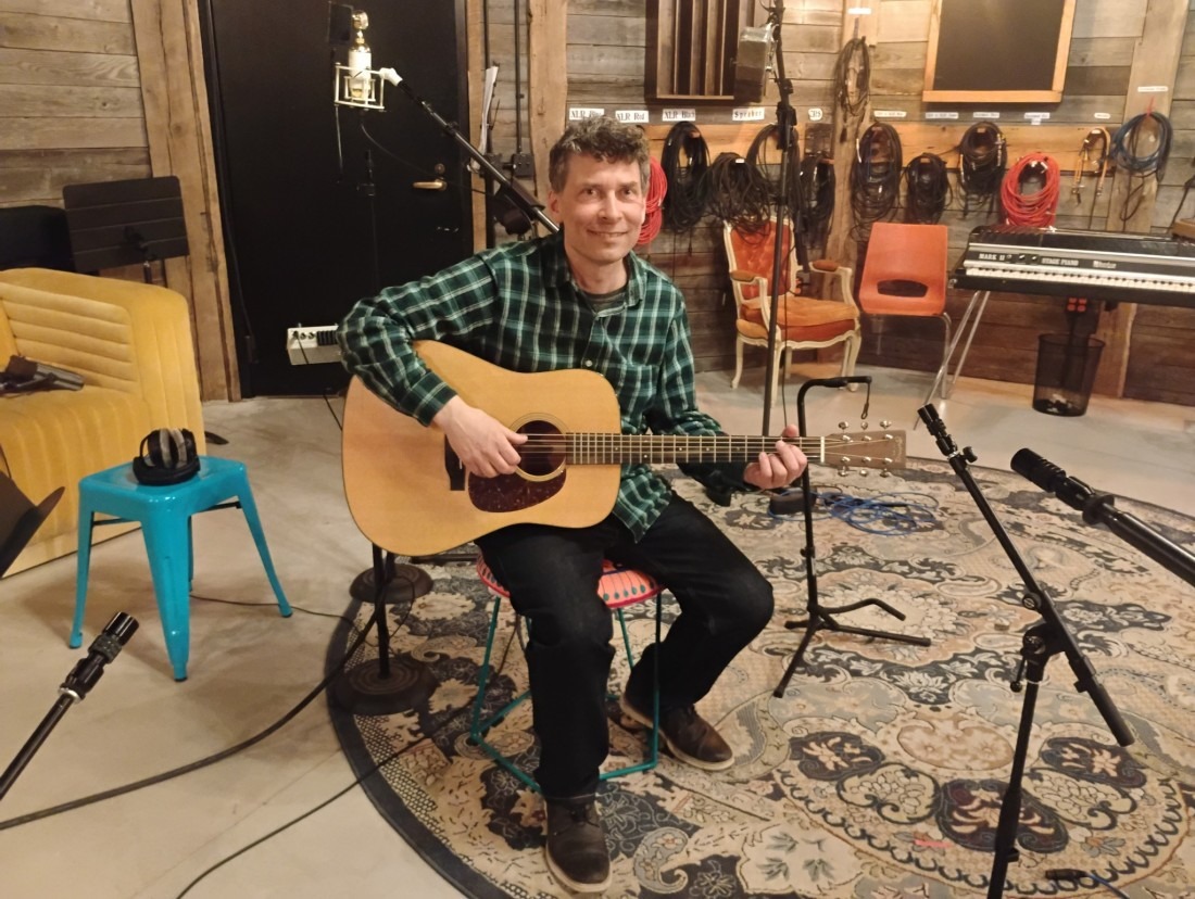 a man playing an acoustic guitar in a recording studio