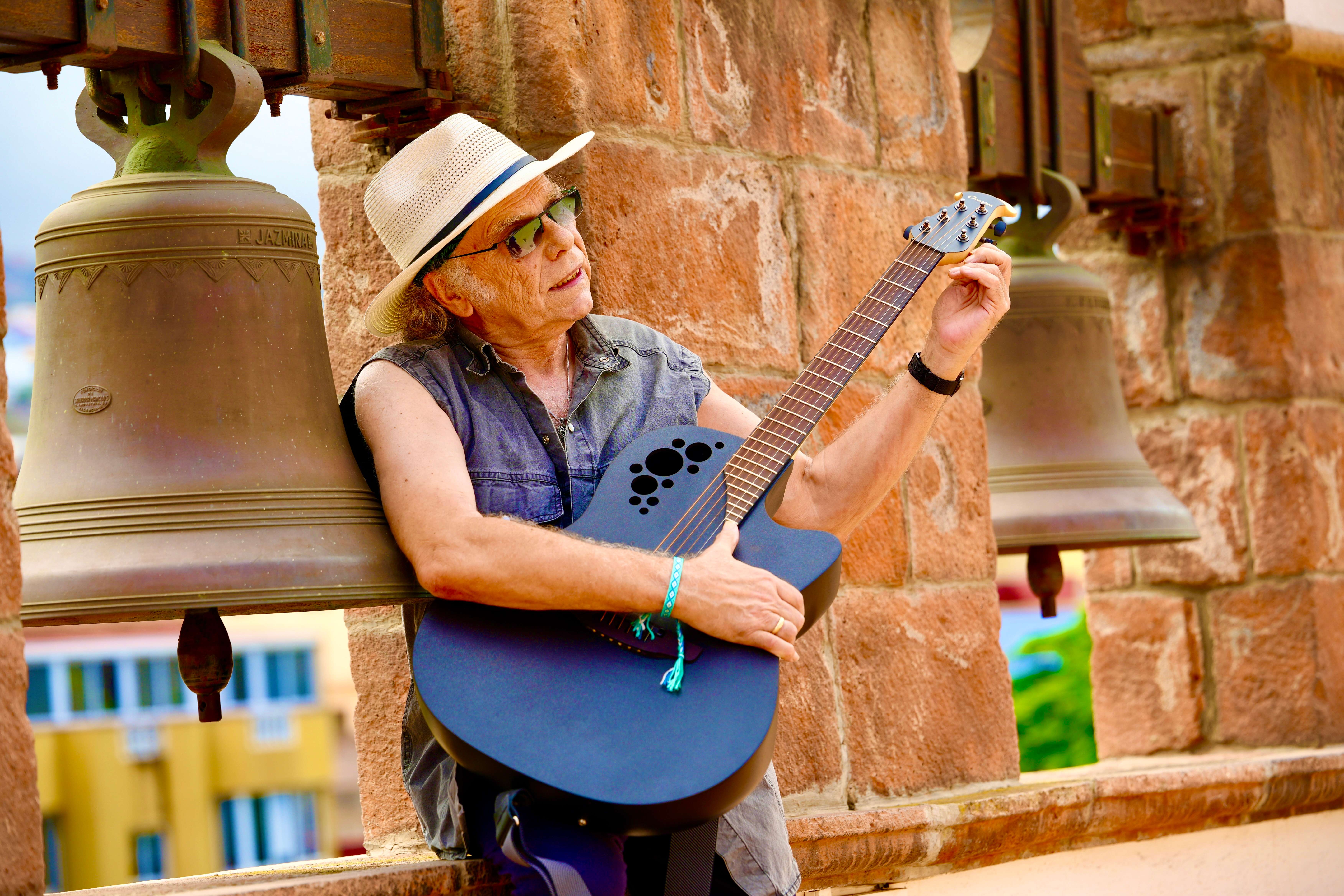 a man in a hat is playing an acoustic guitar