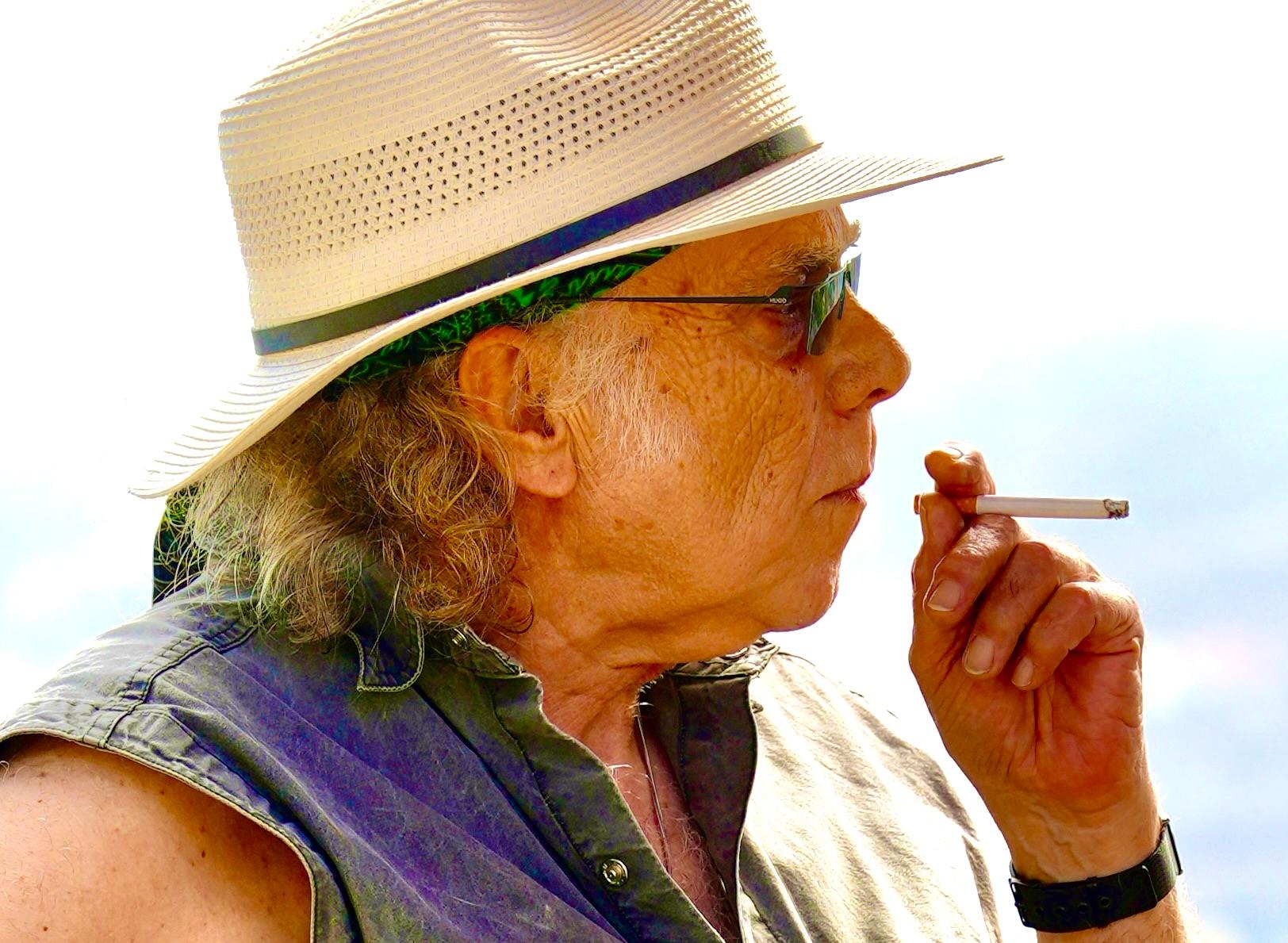 a man wearing a hat smoking a cigarette