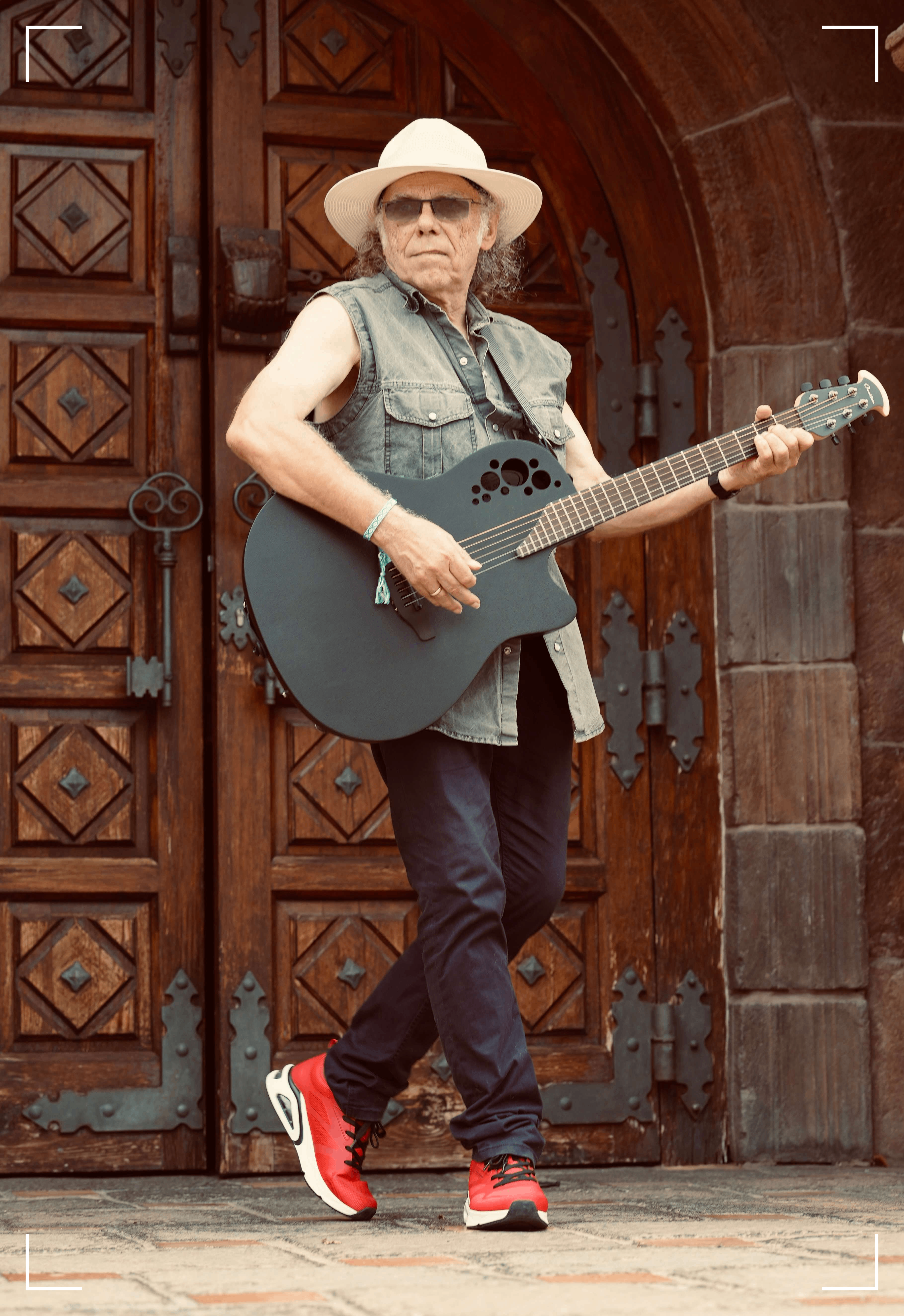 a man in a hat holding an acoustic guitar