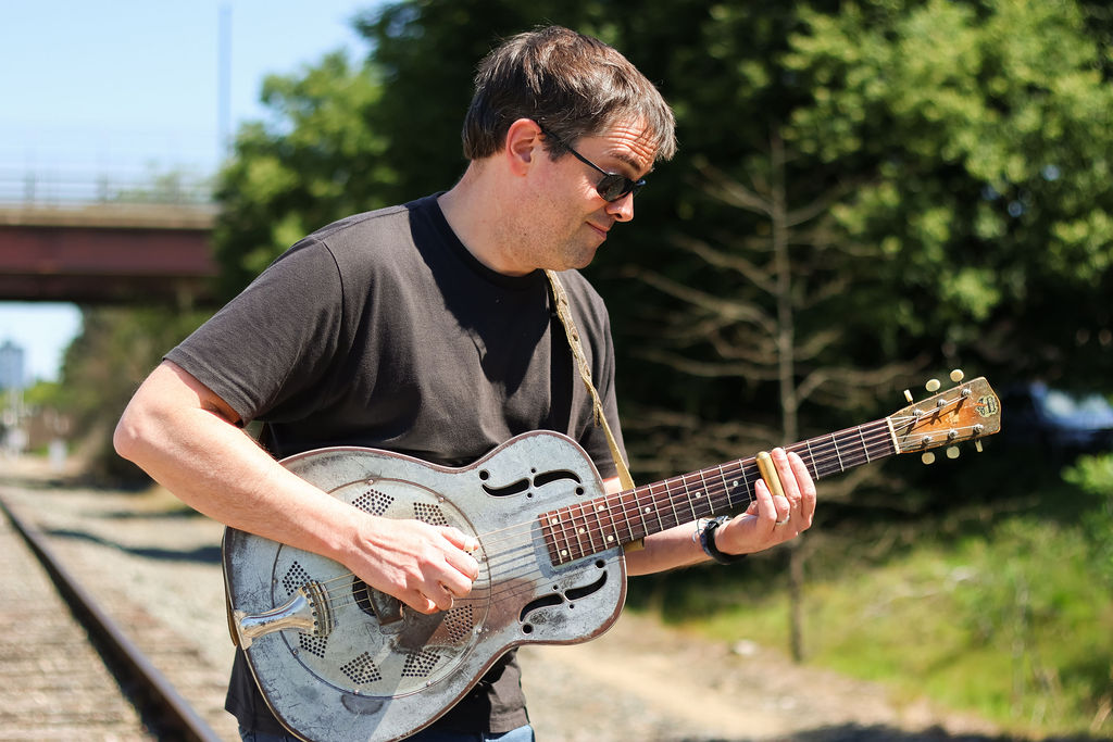 a man playing a guitar on a train track