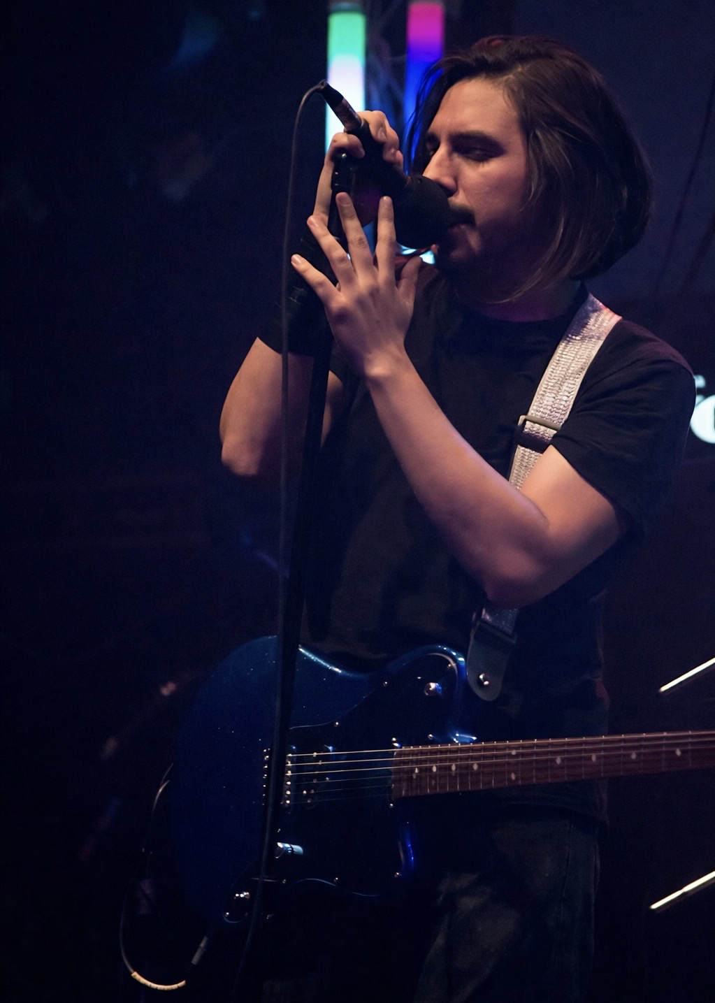 a man holding a guitar and singing into a microphone