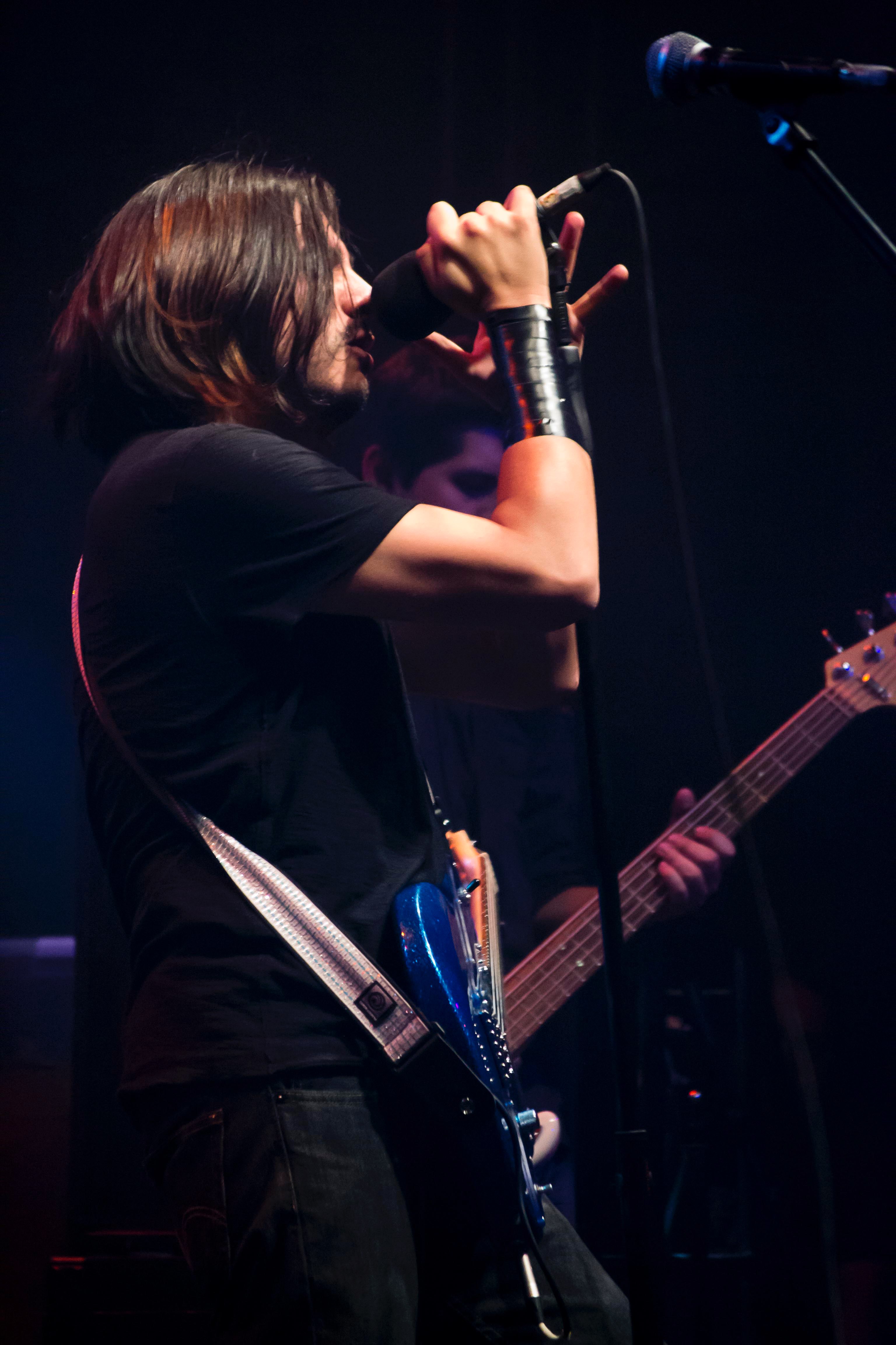 a man singing into a microphone while holding a guitar