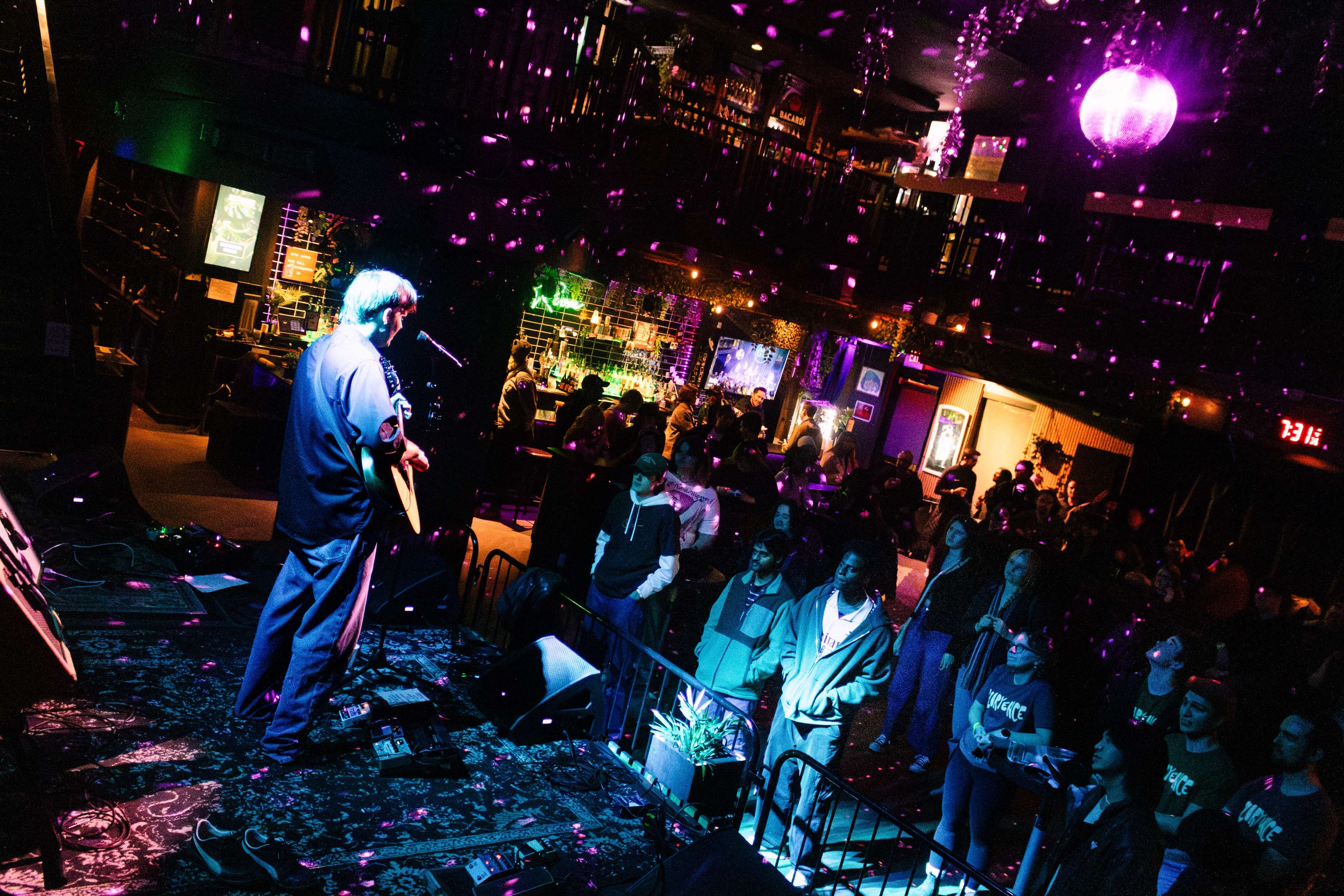 a man is playing a guitar in front of a crowd of people