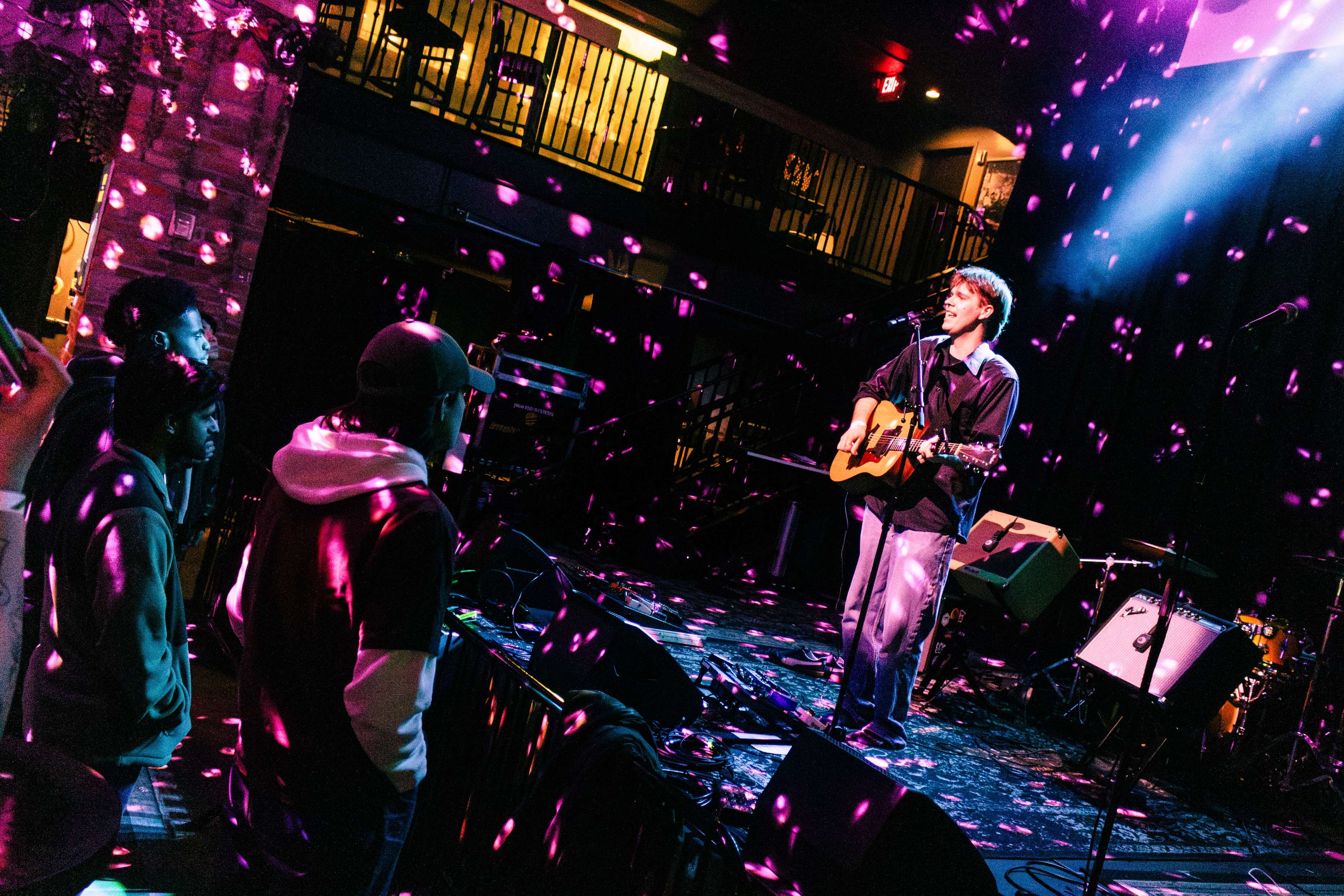 a man playing an acoustic guitar in front of confetti