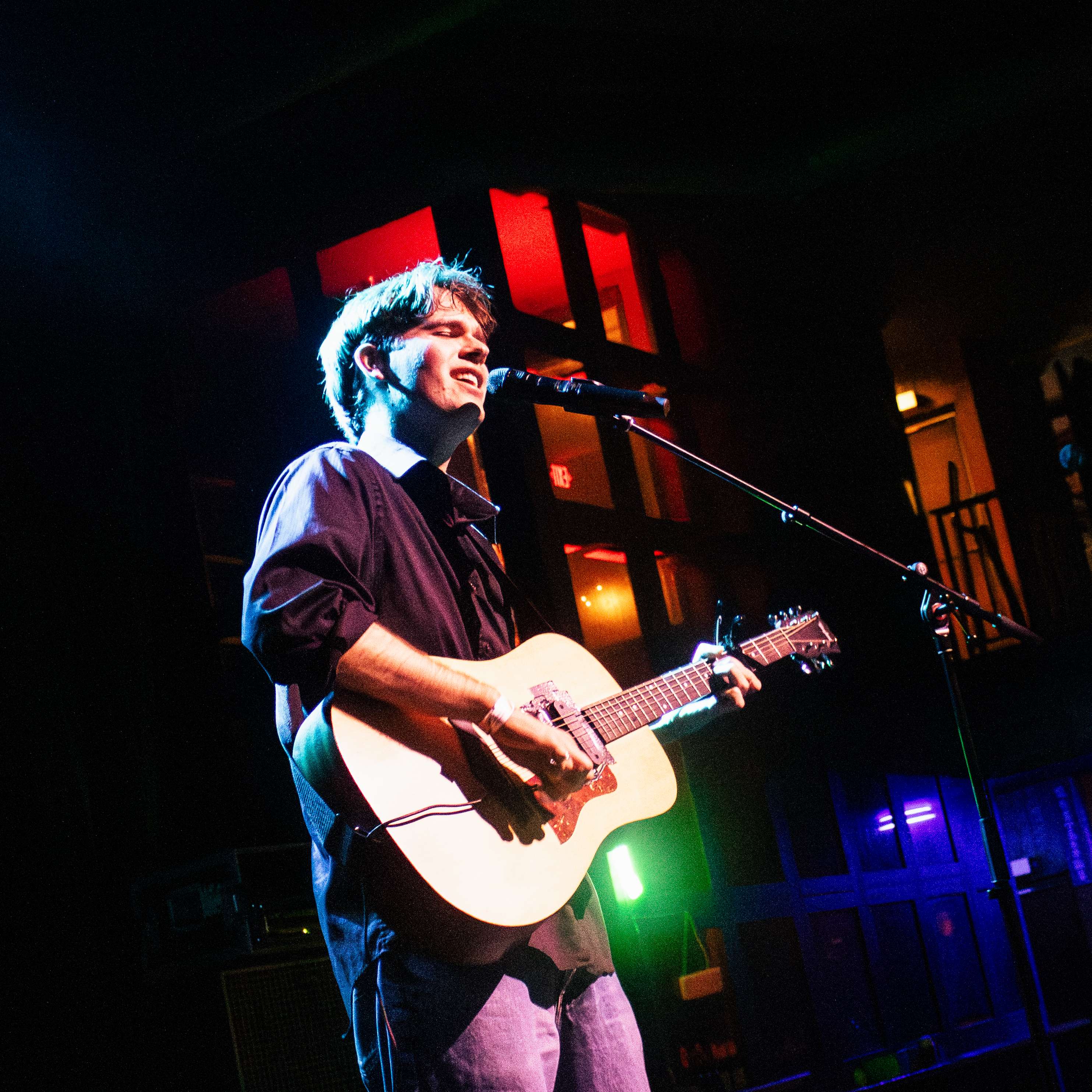 a man playing an acoustic guitar in front of a microphone