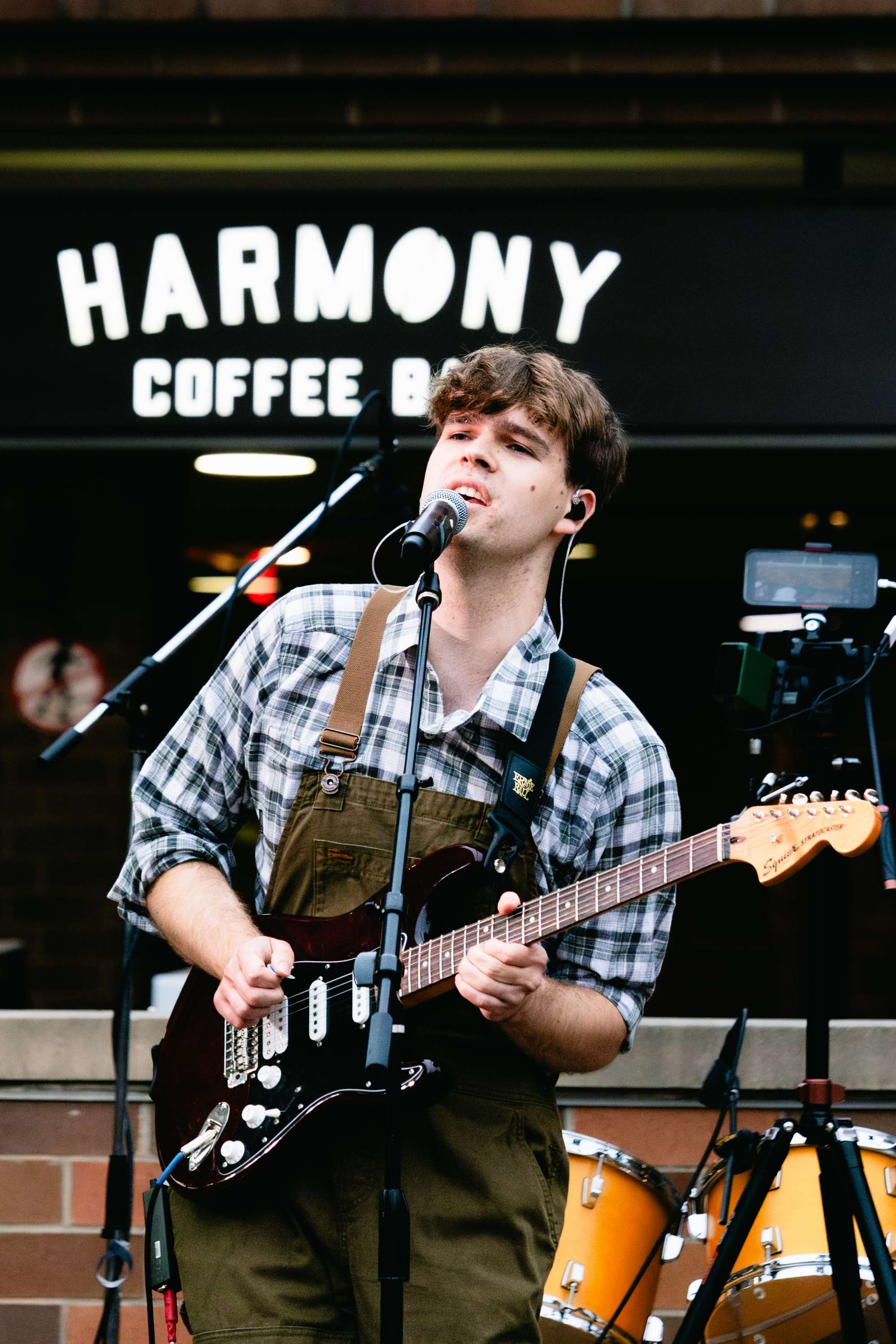 a young man playing guitar in front of a coffee shop