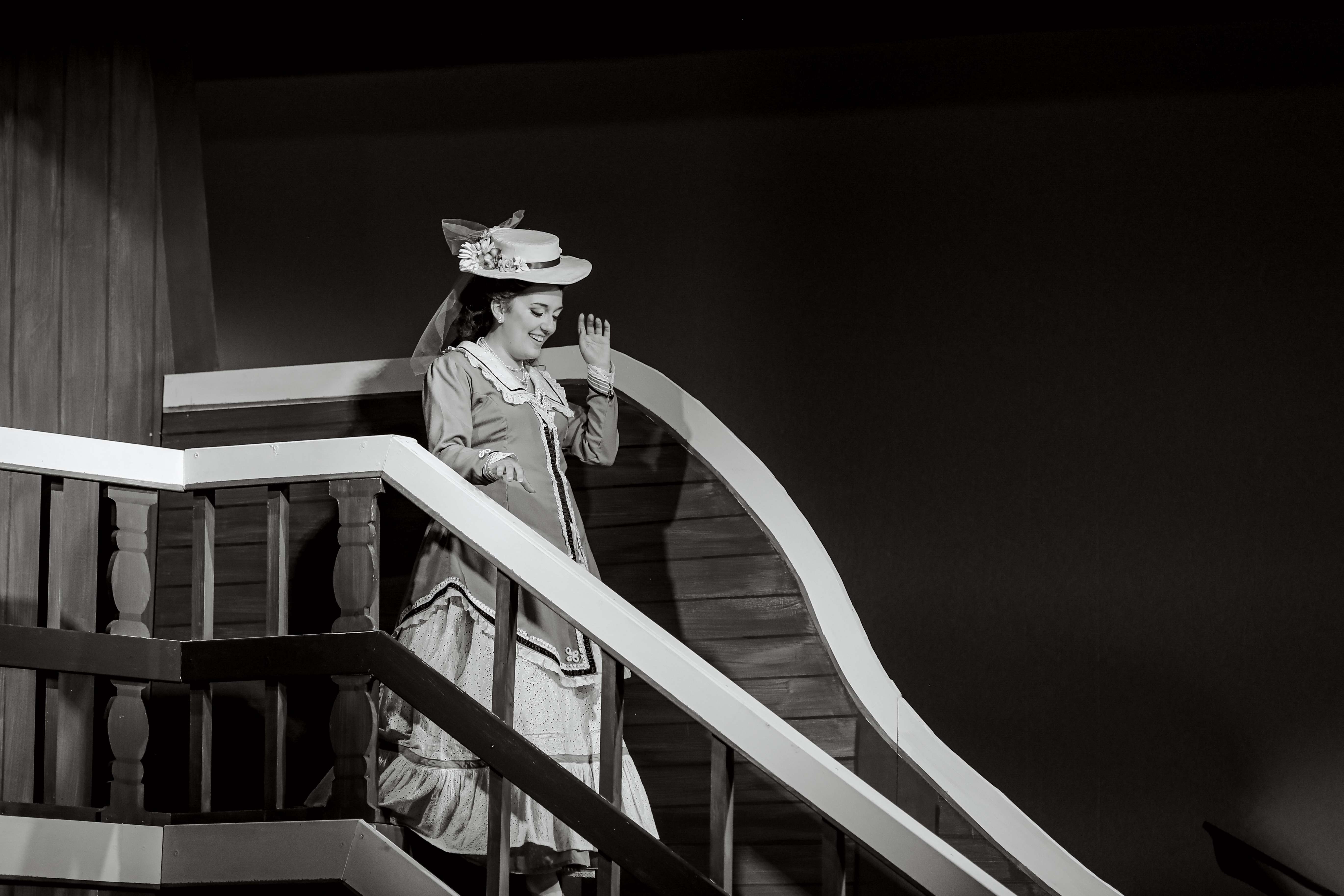 a woman in a period dress standing on a staircase
