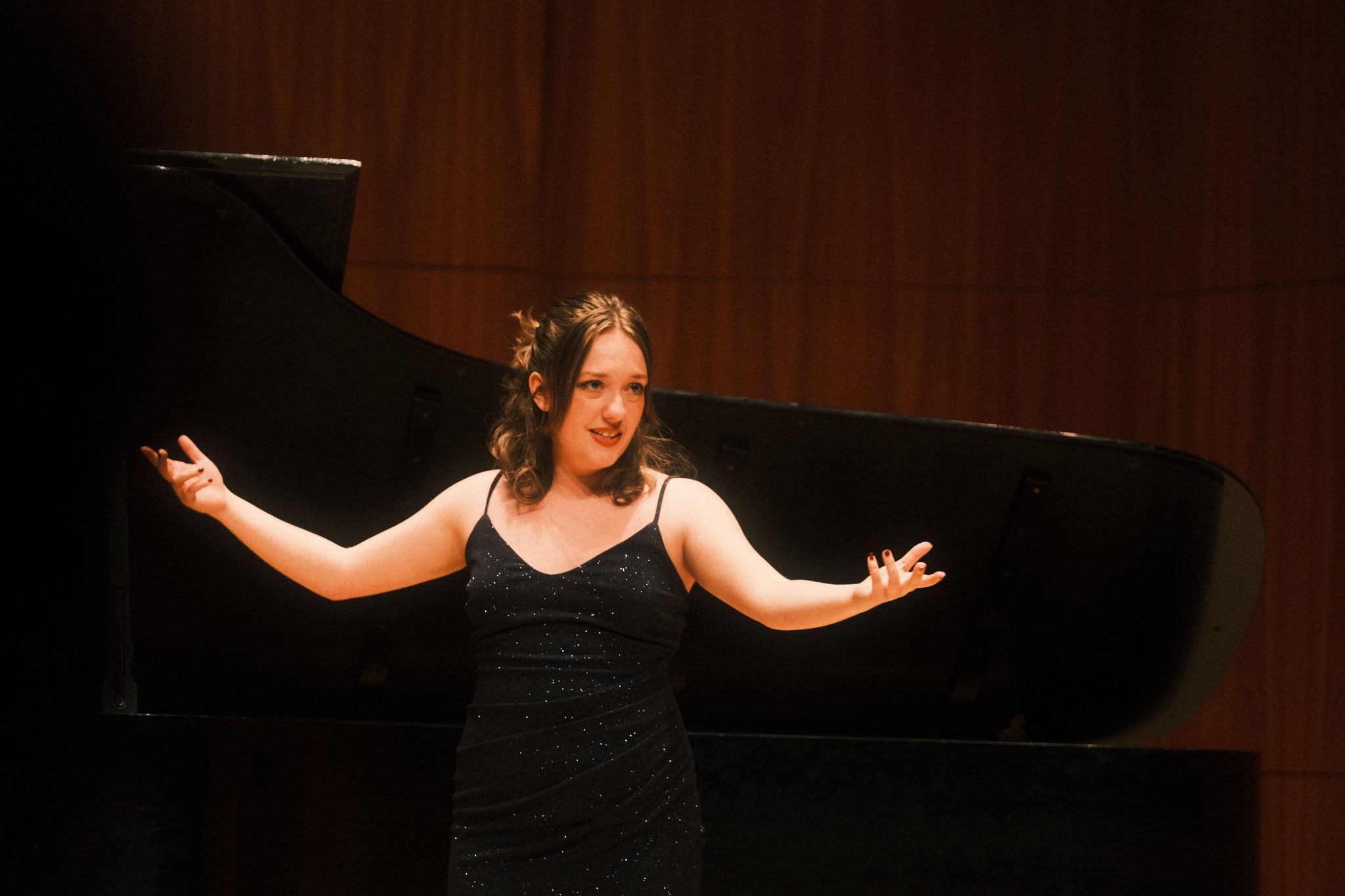a woman in a black dress standing in front of a piano