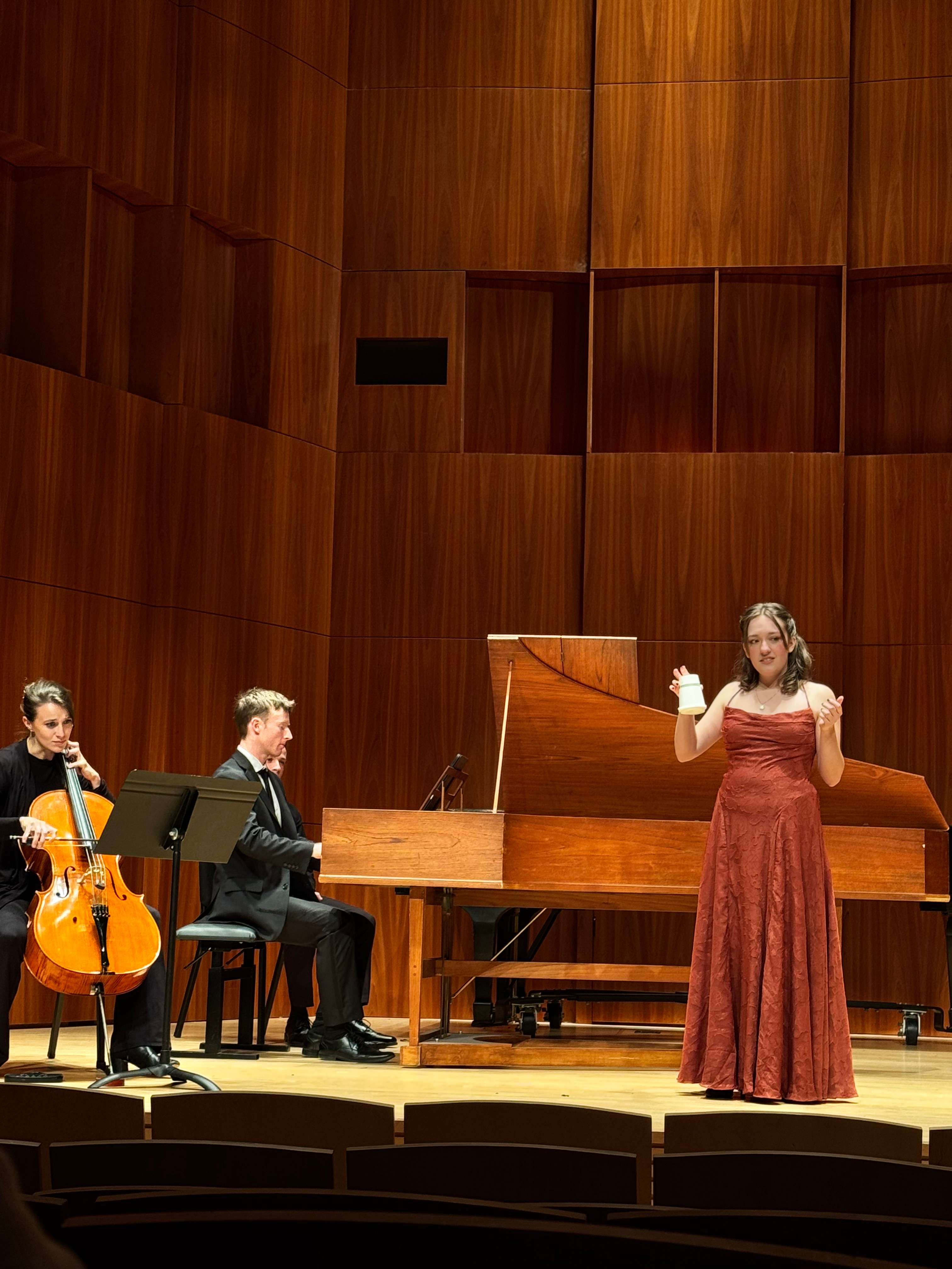a woman in a red dress is standing in front of a group of musicians