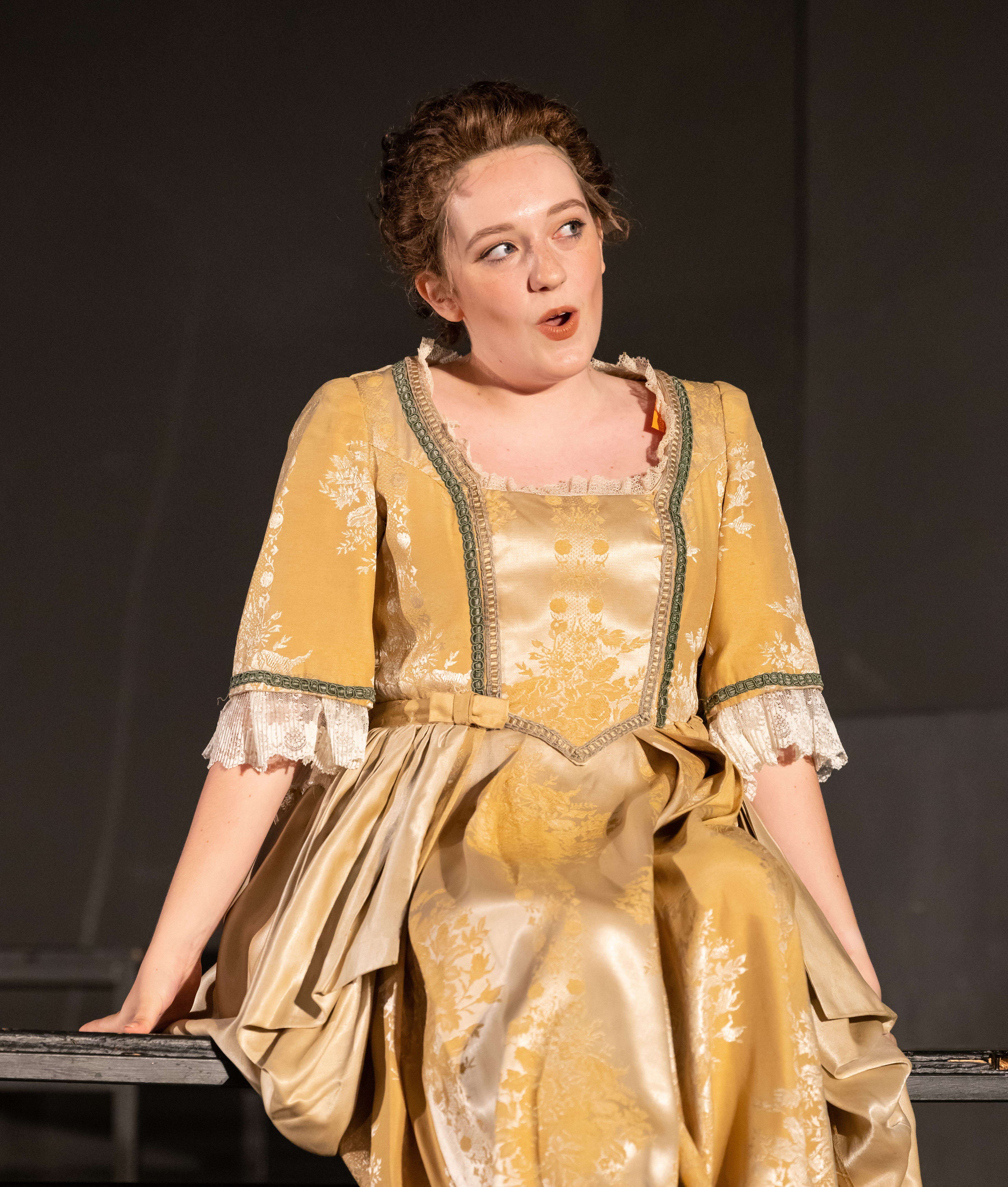 a woman in a yellow dress sitting on a bench