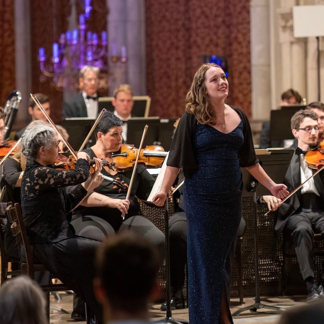 a woman in a dress singing in front of an orchestra
