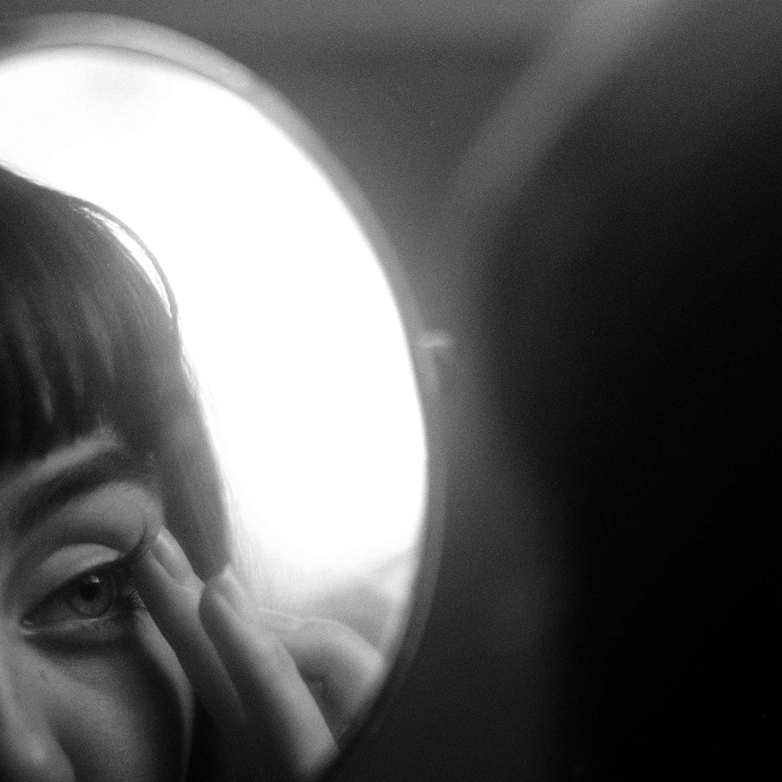 a black and white photo of a woman looking into a mirror