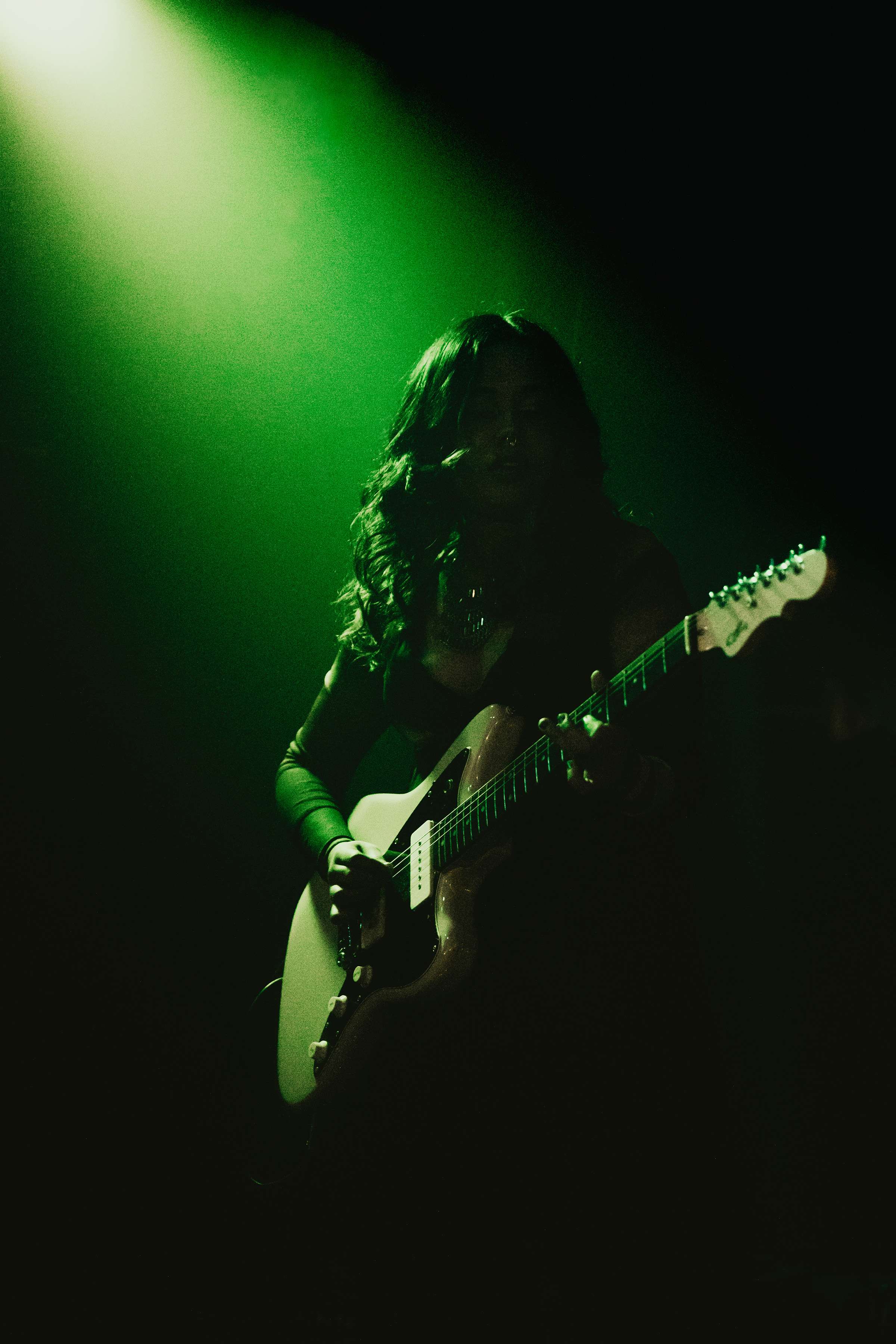 a woman playing an electric guitar in a green light