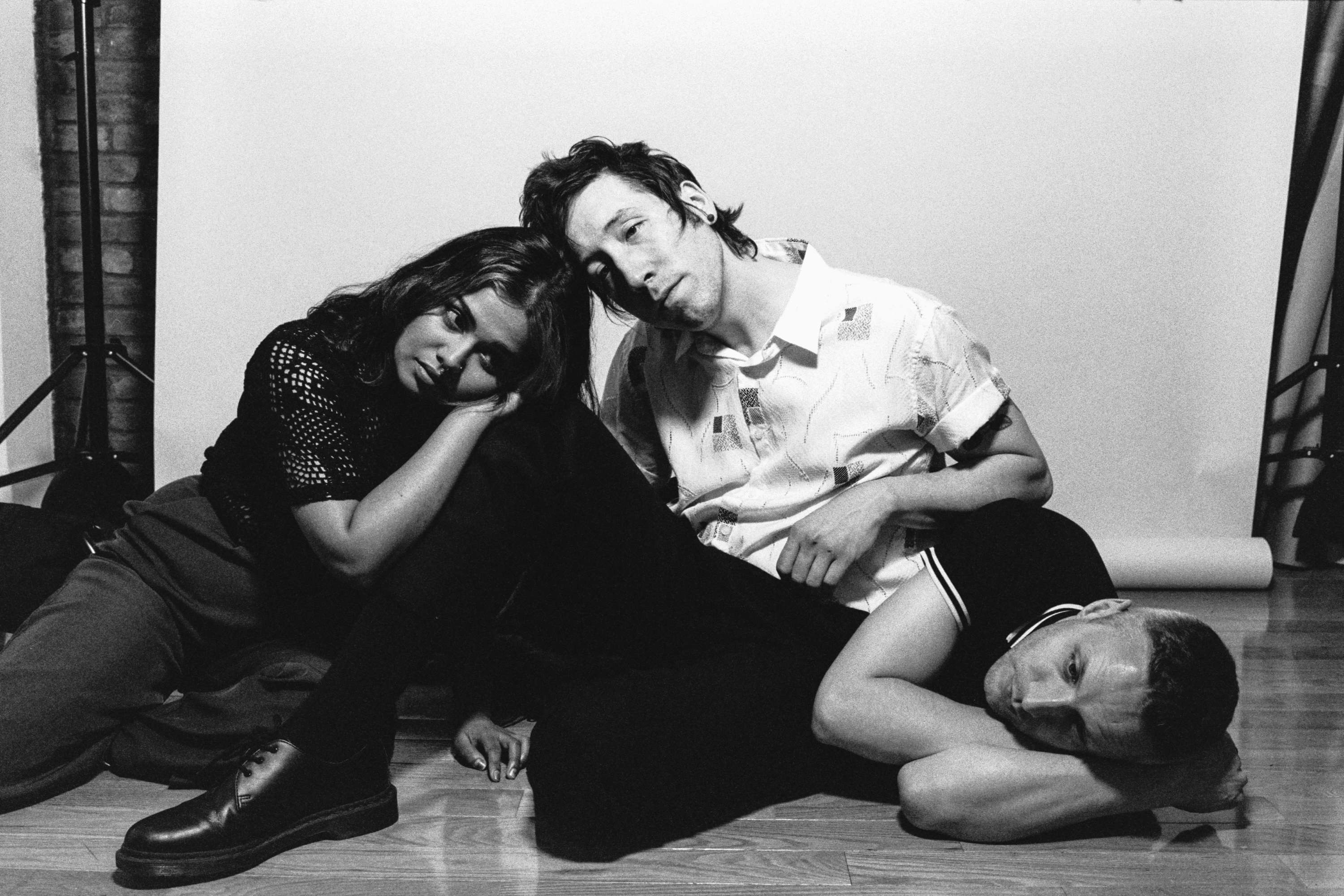 a black and white photo of three people laying on the floor