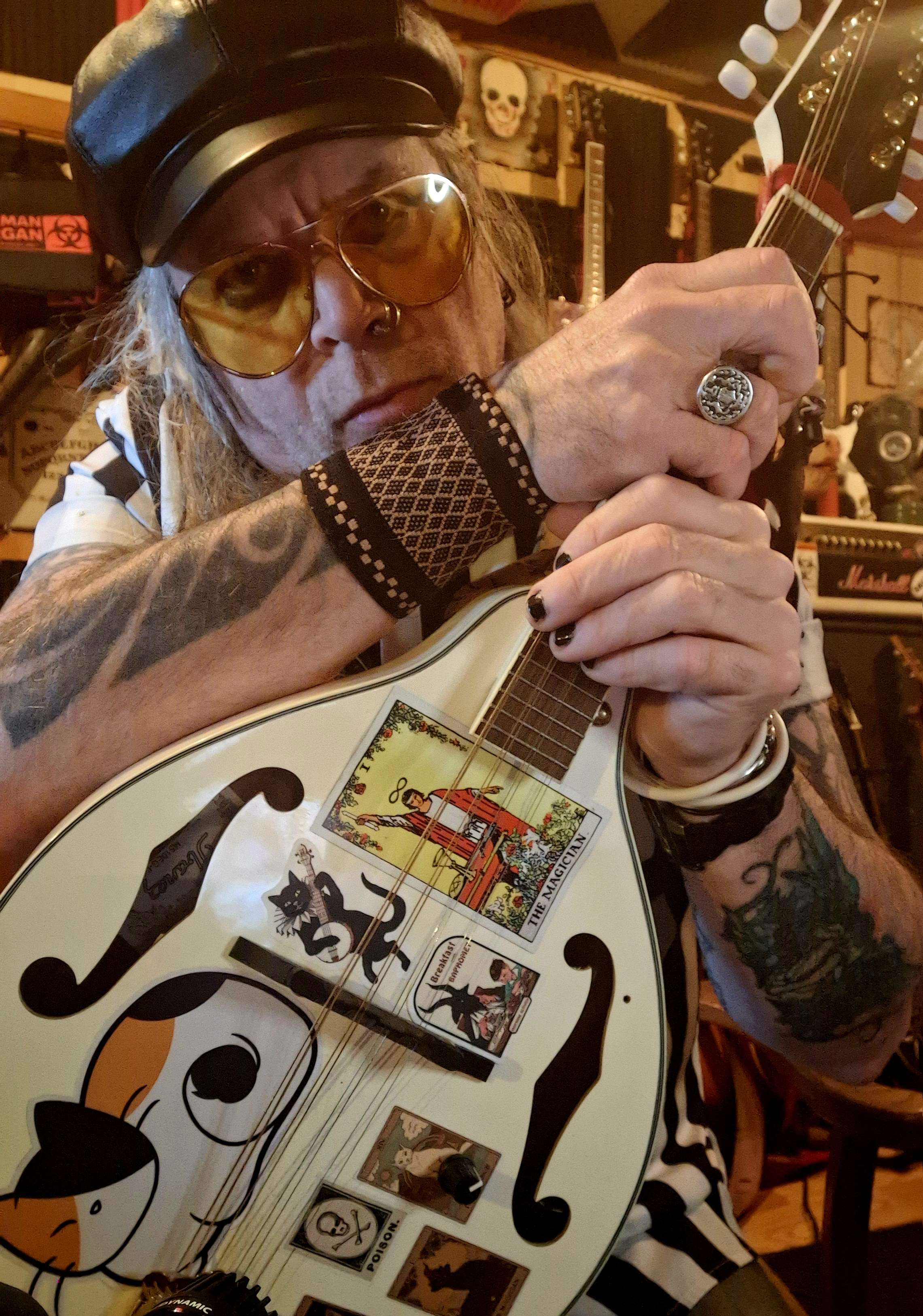 a man wearing a hat and sunglasses holding a guitar