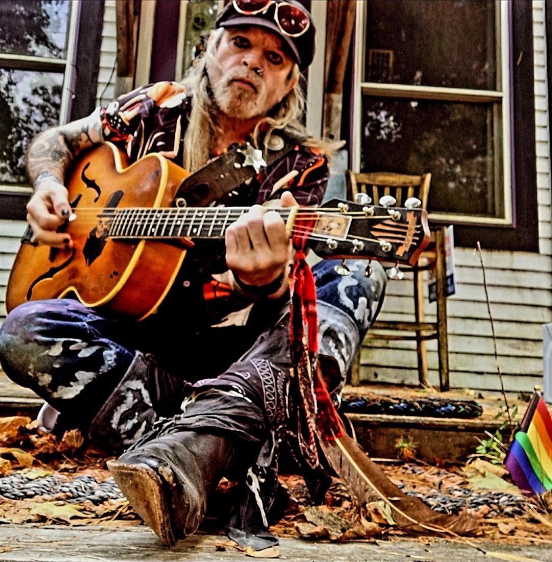 a man with a guitar sitting on a porch
