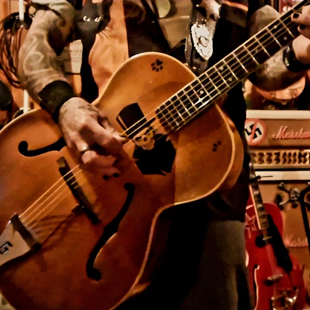 a man with tattoos playing a guitar in a garage