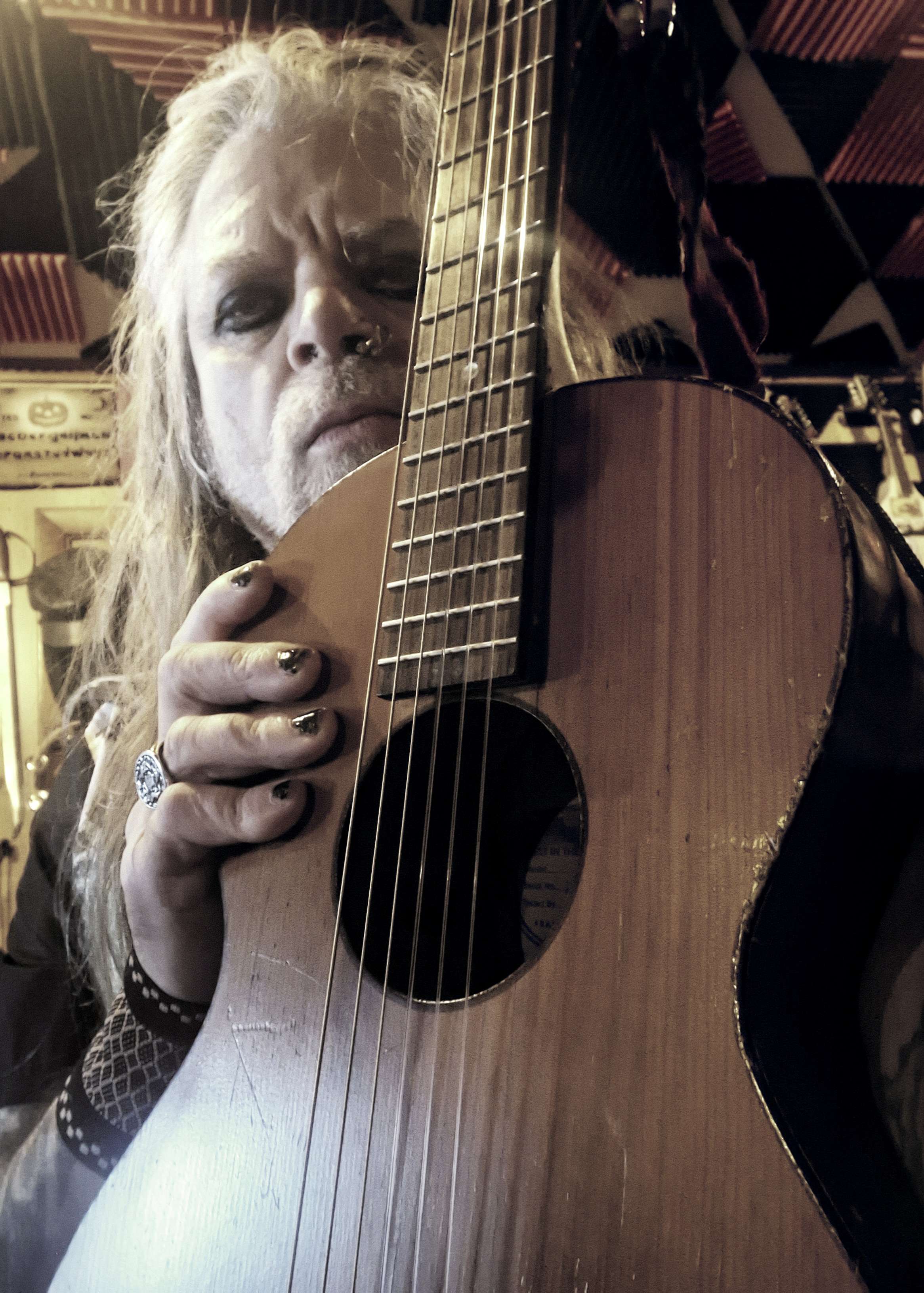 a man with long hair holding an acoustic guitar