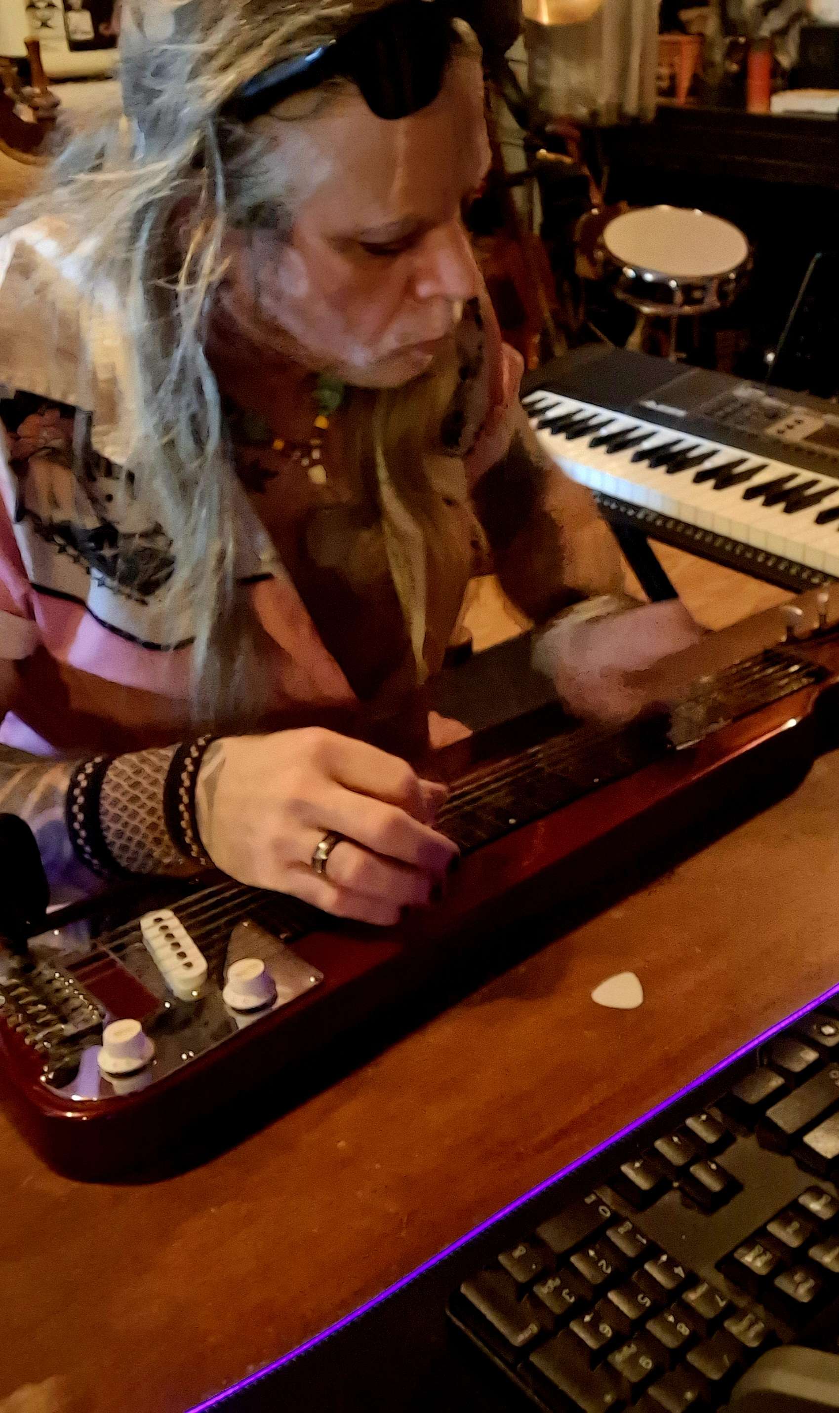 a woman playing a guitar in front of a keyboard