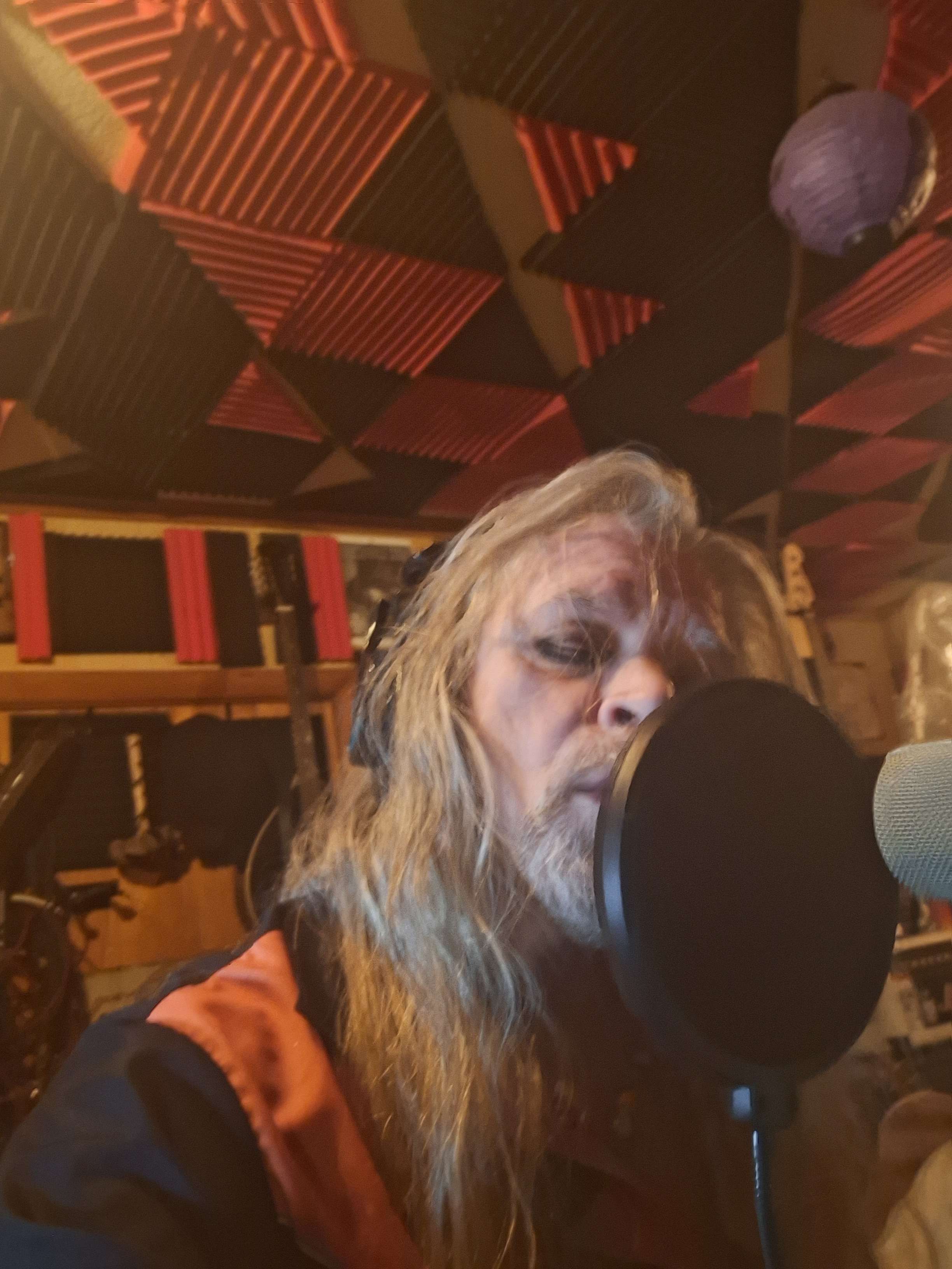 a man with long hair is singing into a microphone