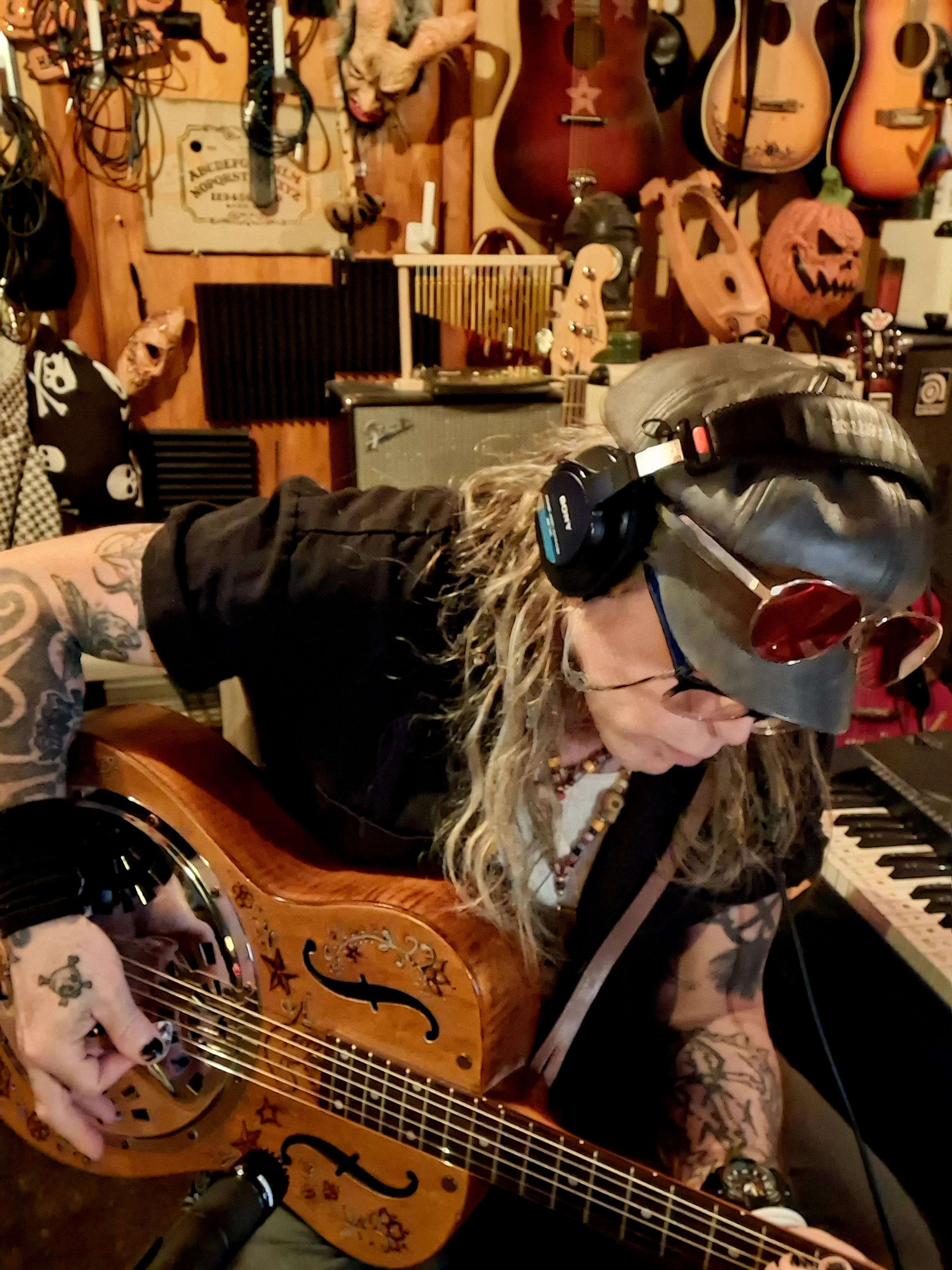 a man with tattoos playing an acoustic guitar in a recording studio