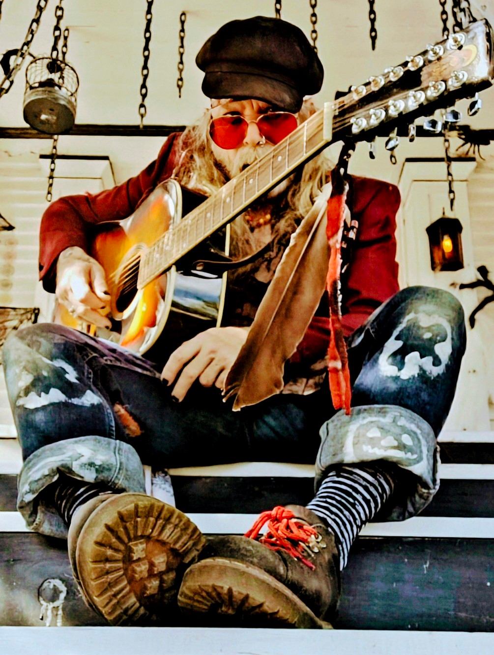 a man sitting on a porch playing an acoustic guitar