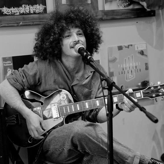 a black and white photo of a man playing an acoustic guitar