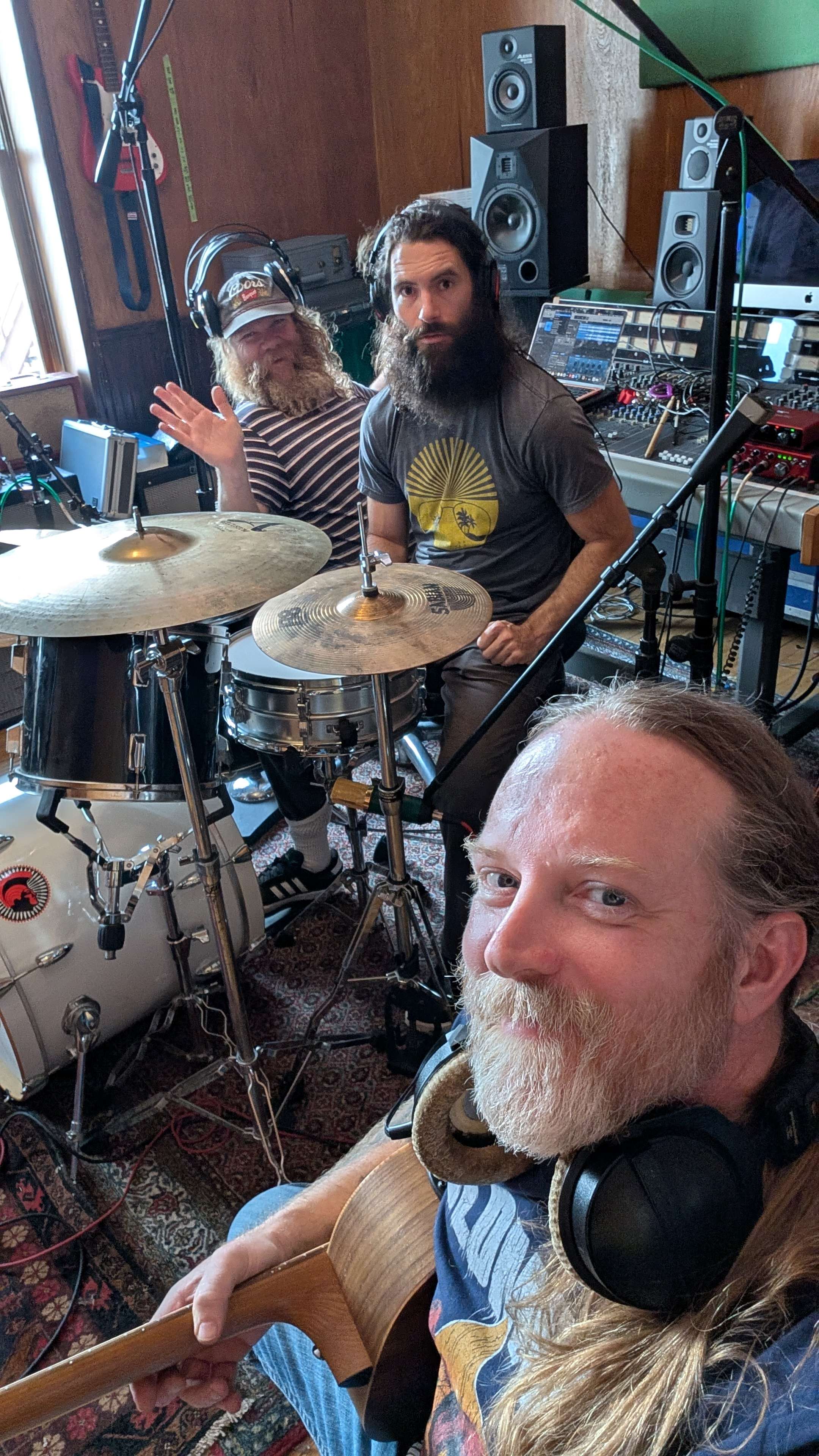 a group of people in a recording studio with a guitar and drums
