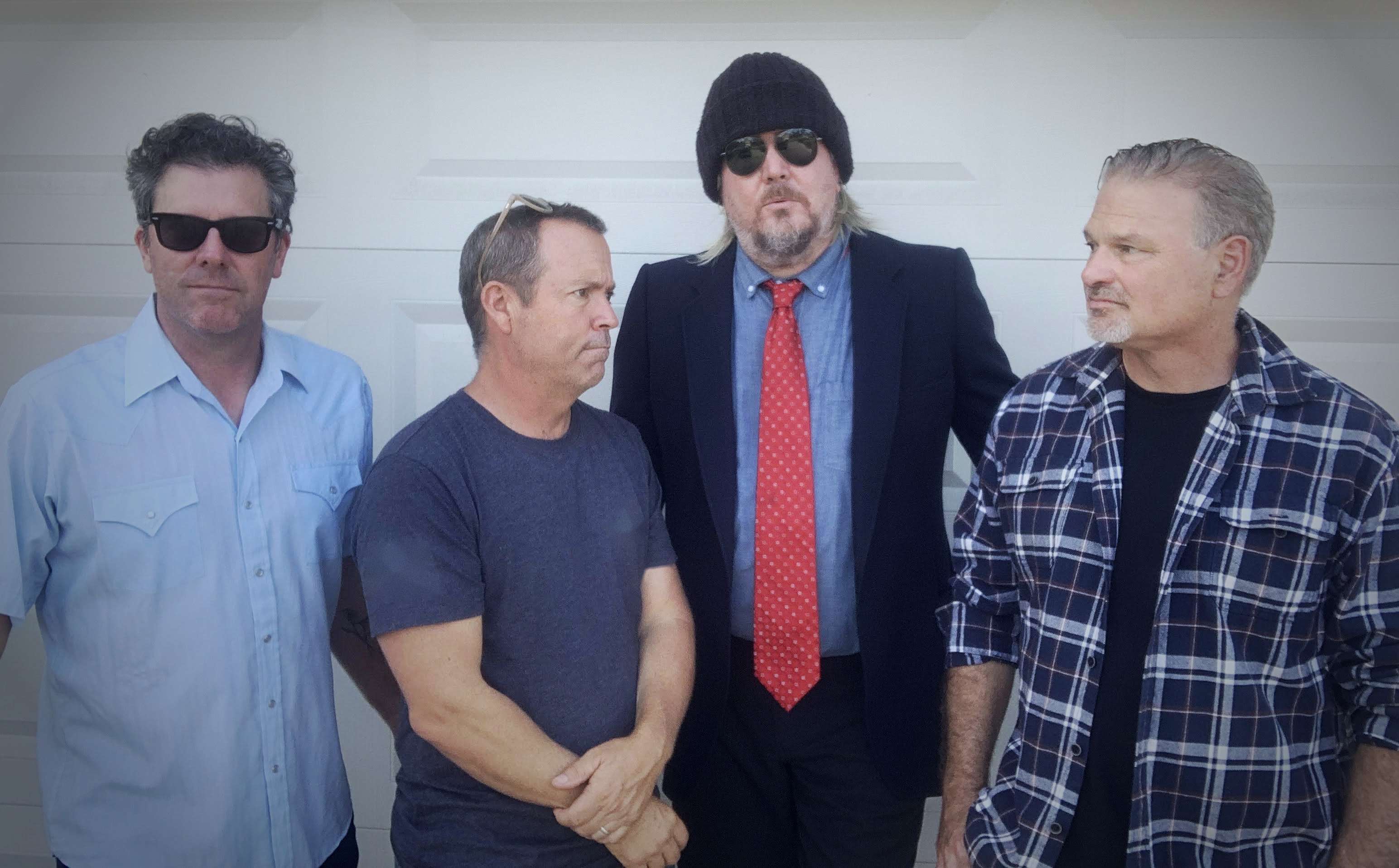 four men standing next to each other in front of a garage