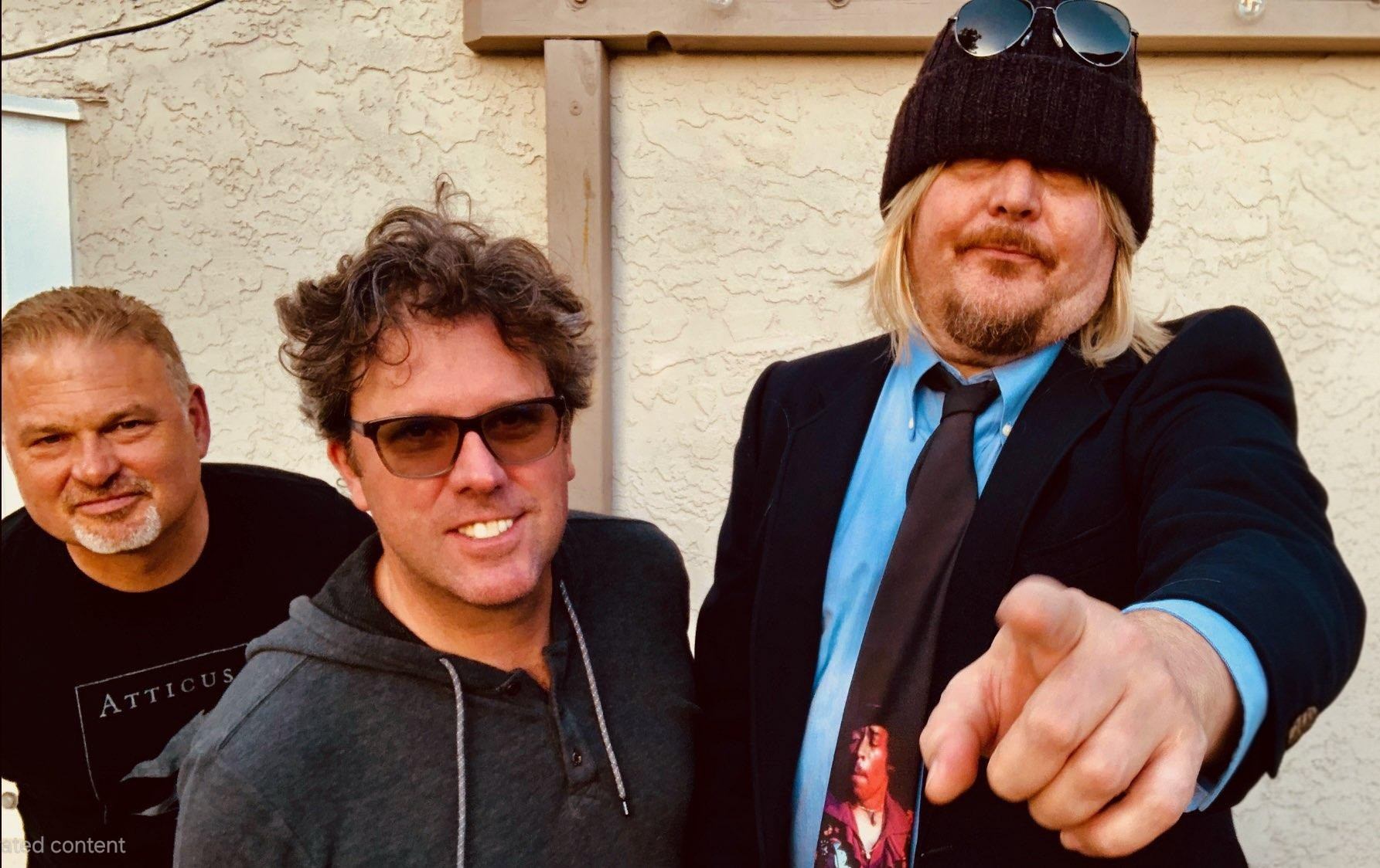 three men posing for a picture with one pointing to the camera