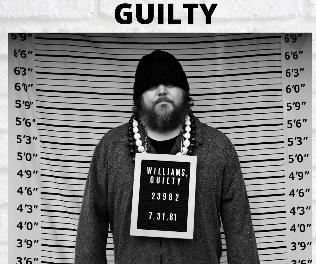 a man with a beard standing in front of a mugshot