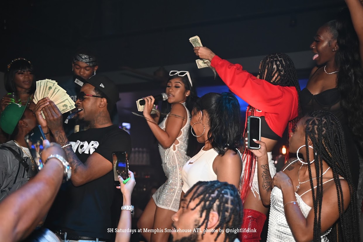 a group of people with money in their hands at a nightclub