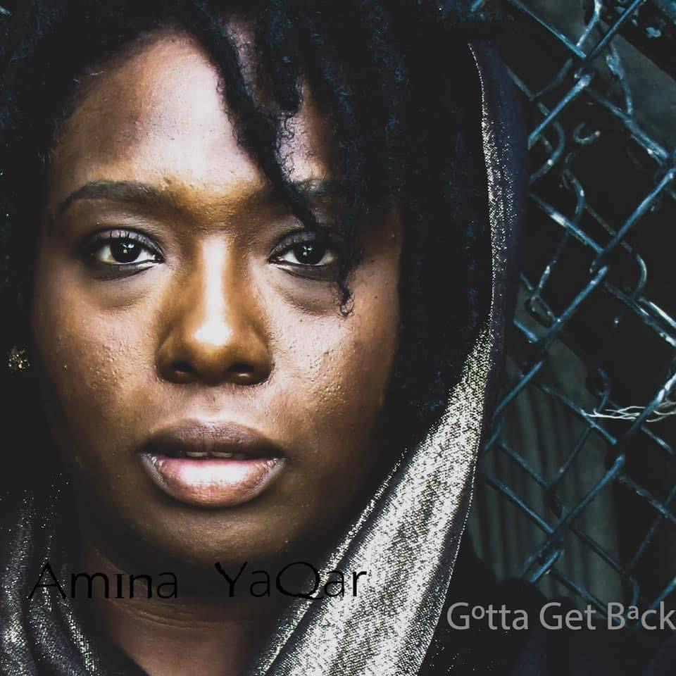 a woman with dreadlocks in front of a fence