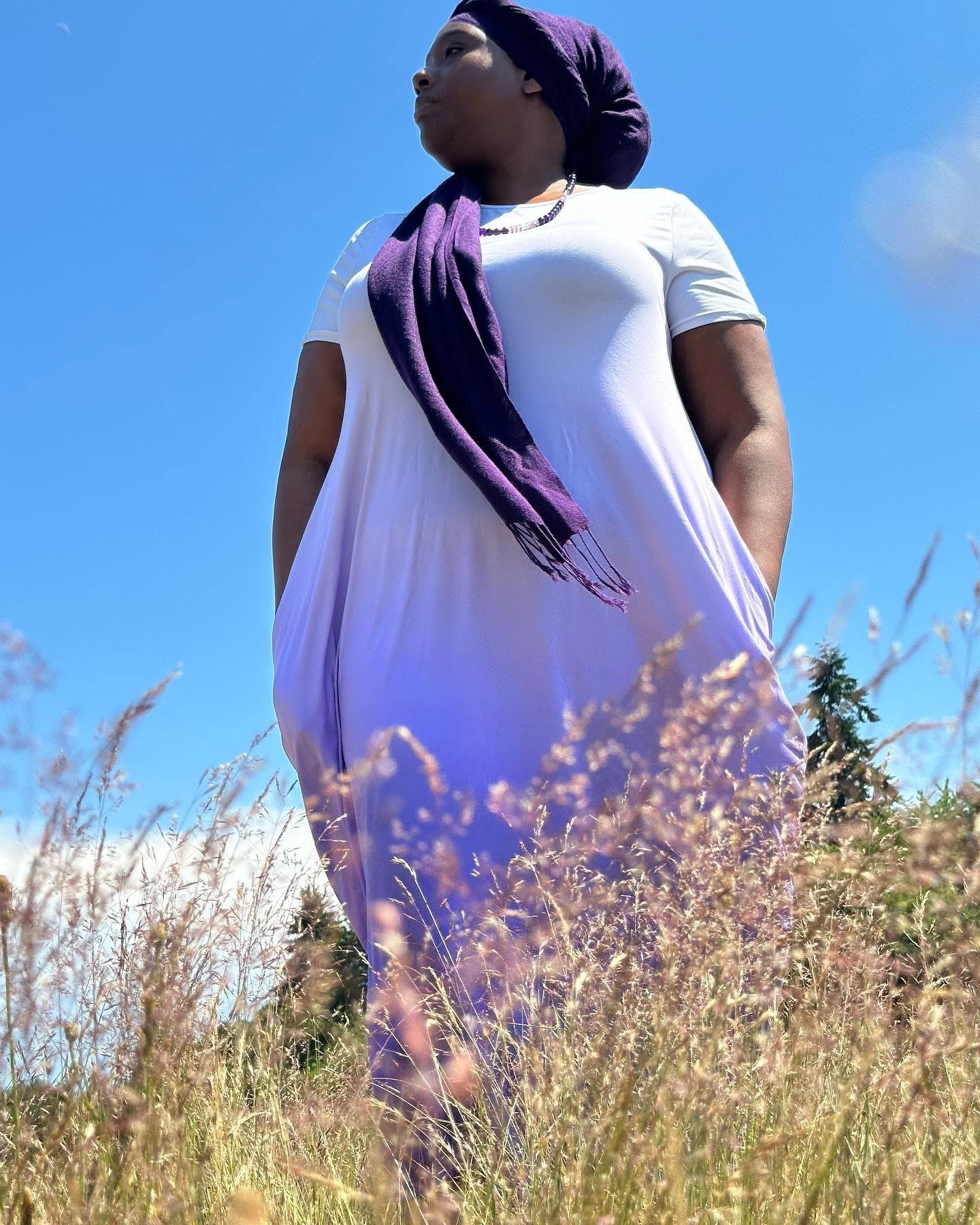 a woman in a purple dress standing in tall grass