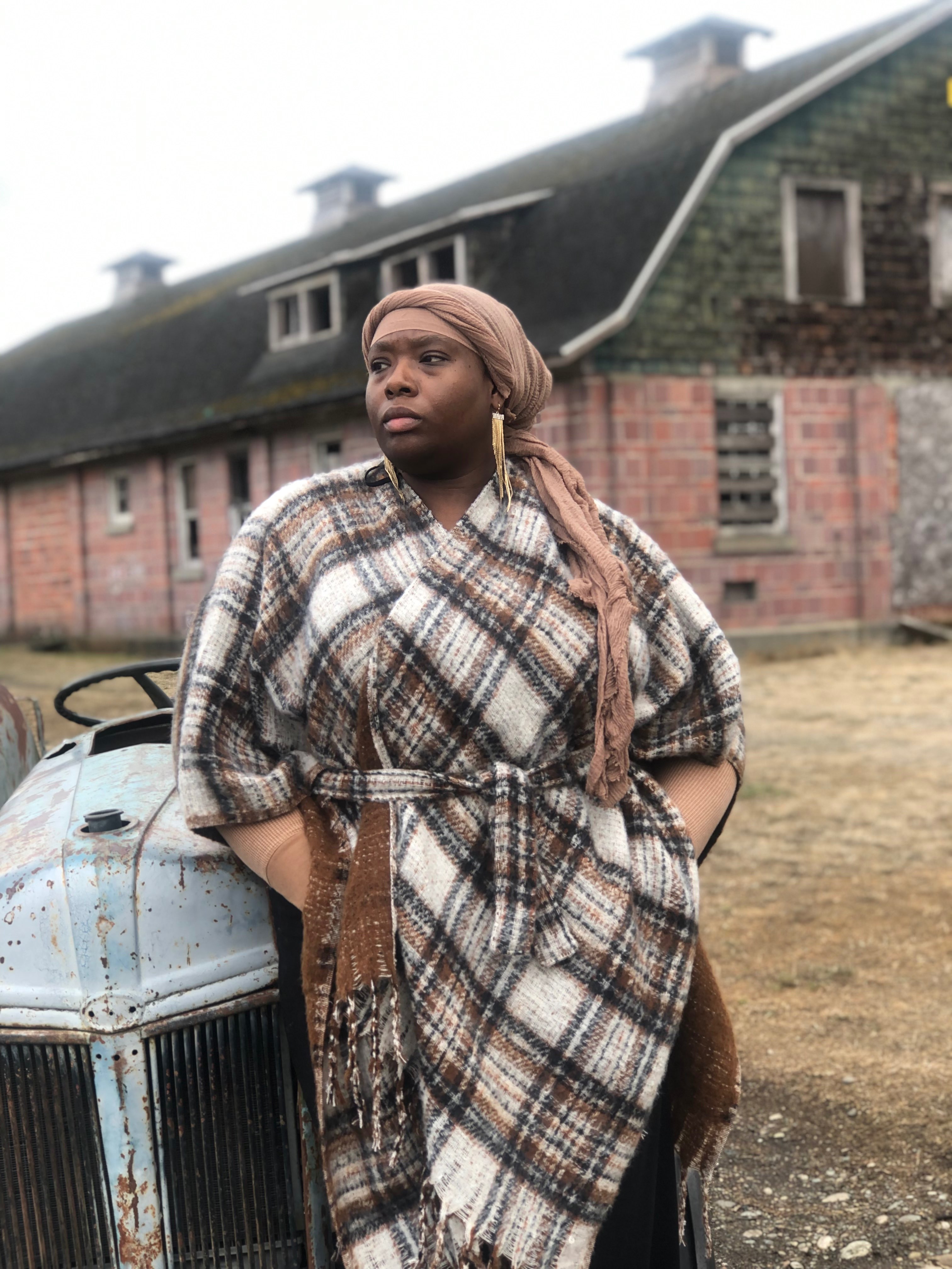 a woman in a plaid coat standing next to an old car