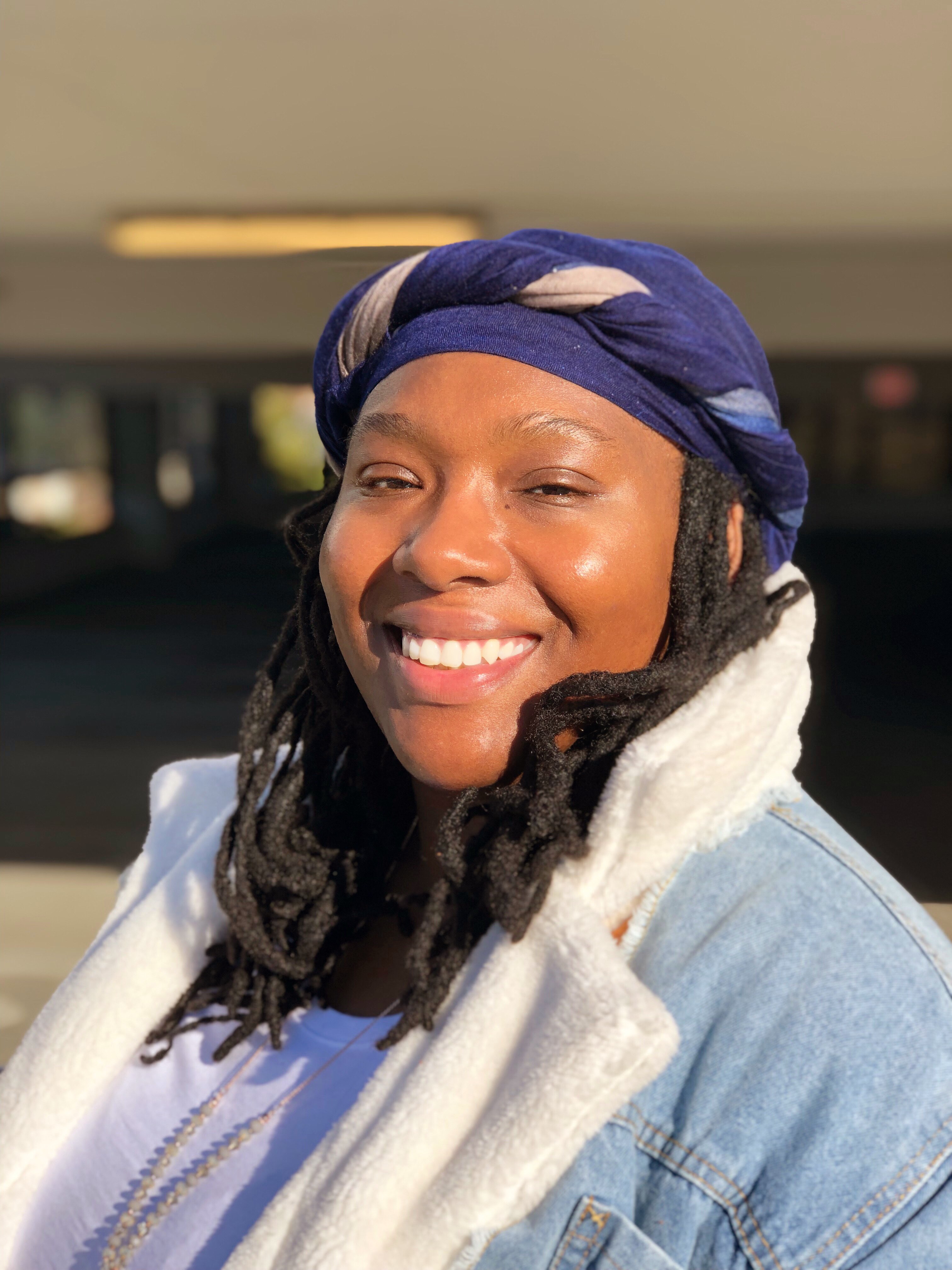 a woman with dreadlocks smiling in a parking lot