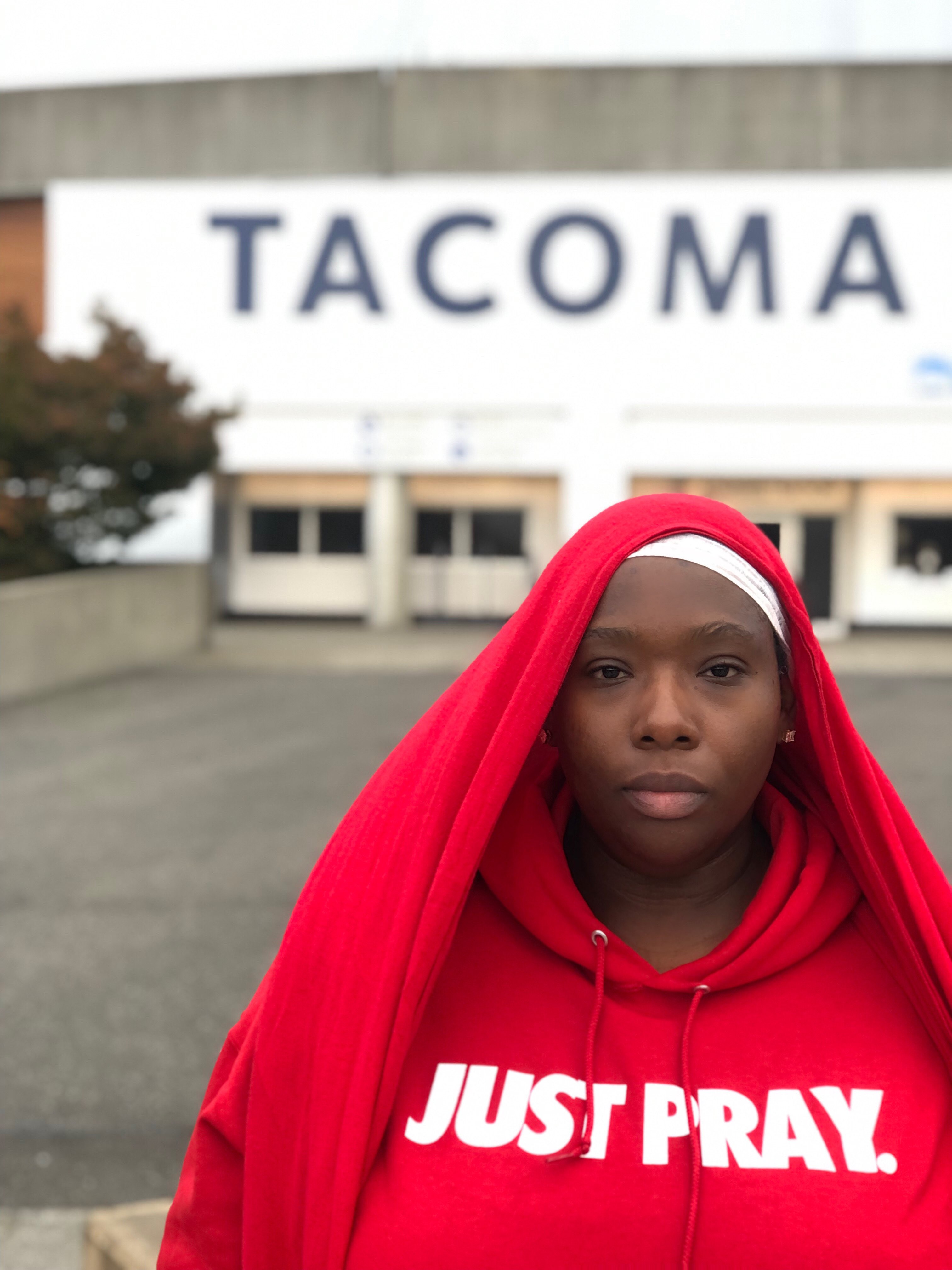 a woman in a red hoodie standing in front of a tacoma stadium
