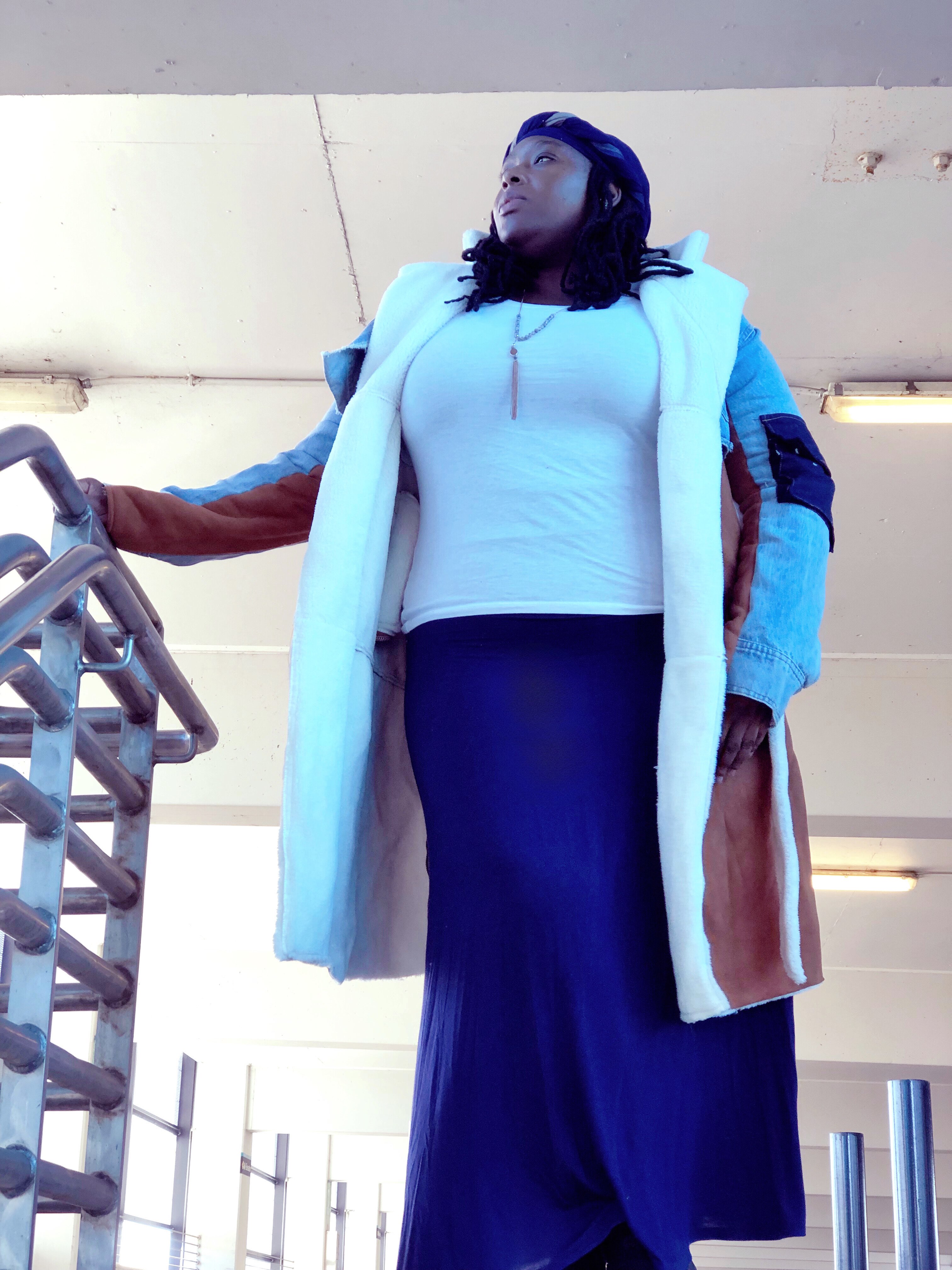 a woman in a blue coat standing on a railing